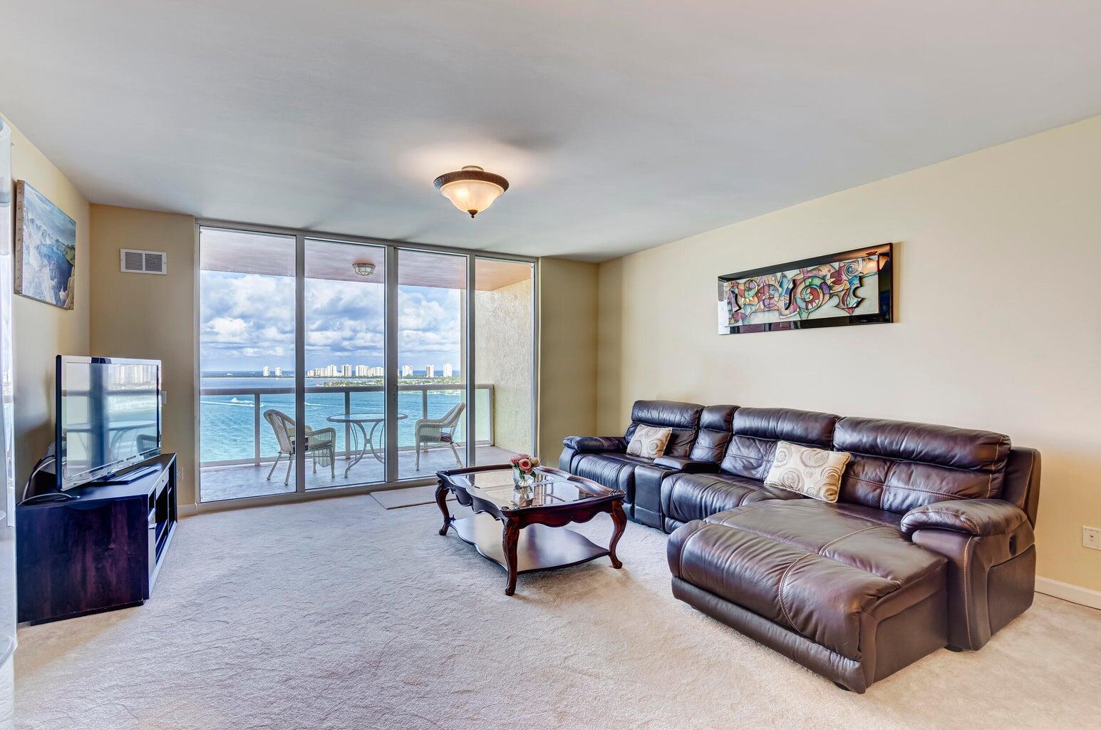 Living room with a leather sectional and balcony doors overlooking the water.
