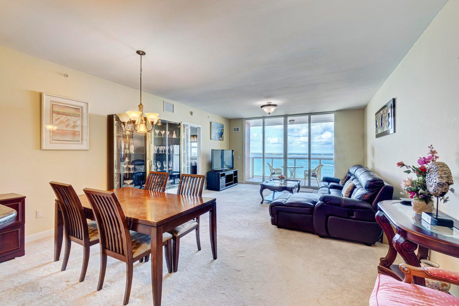 Furnished living and dining area with a leather sectional and ocean views through sliding glass doors.