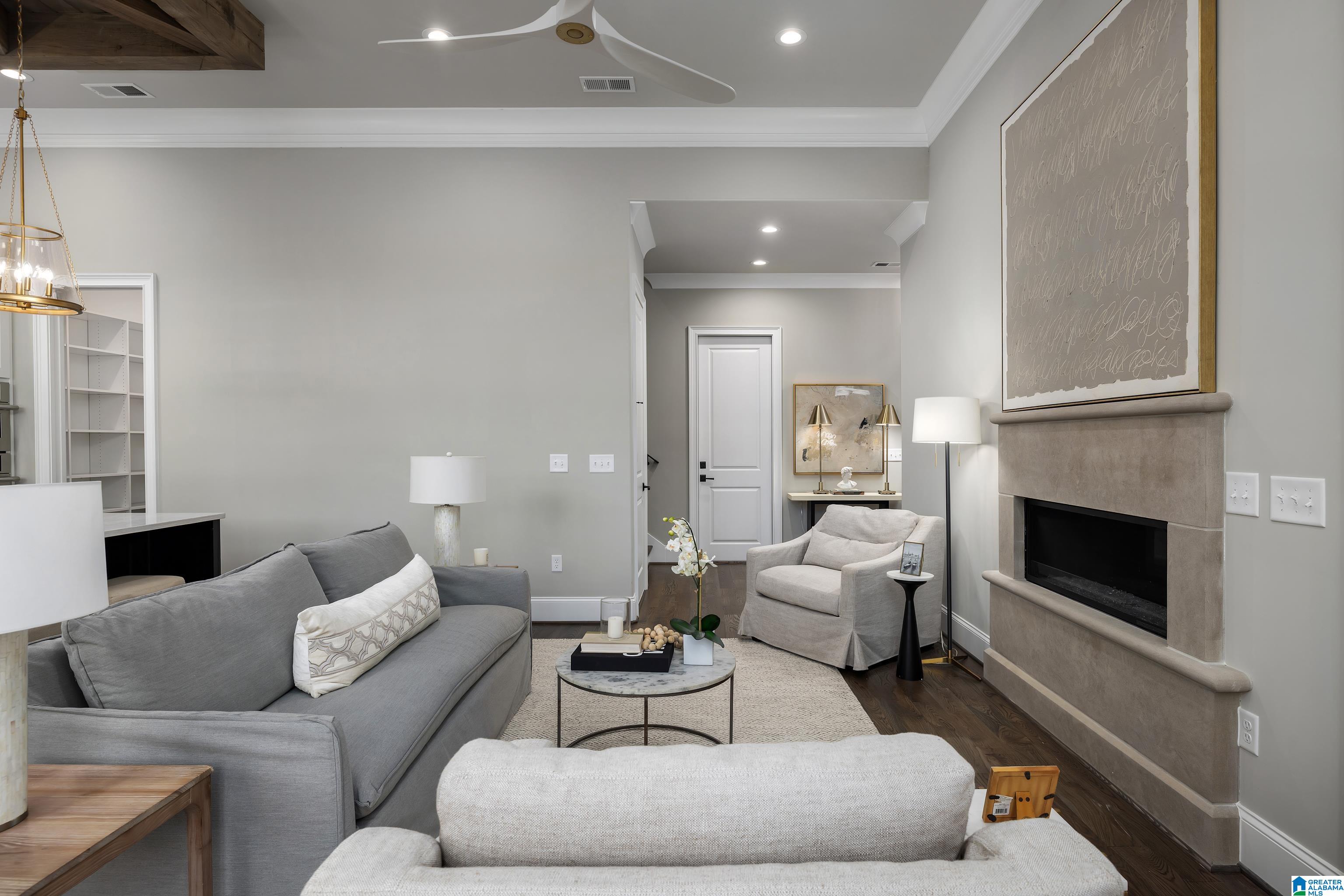 Staged living room with gray sofas, a stone fireplace, and dark hardwood floors.
