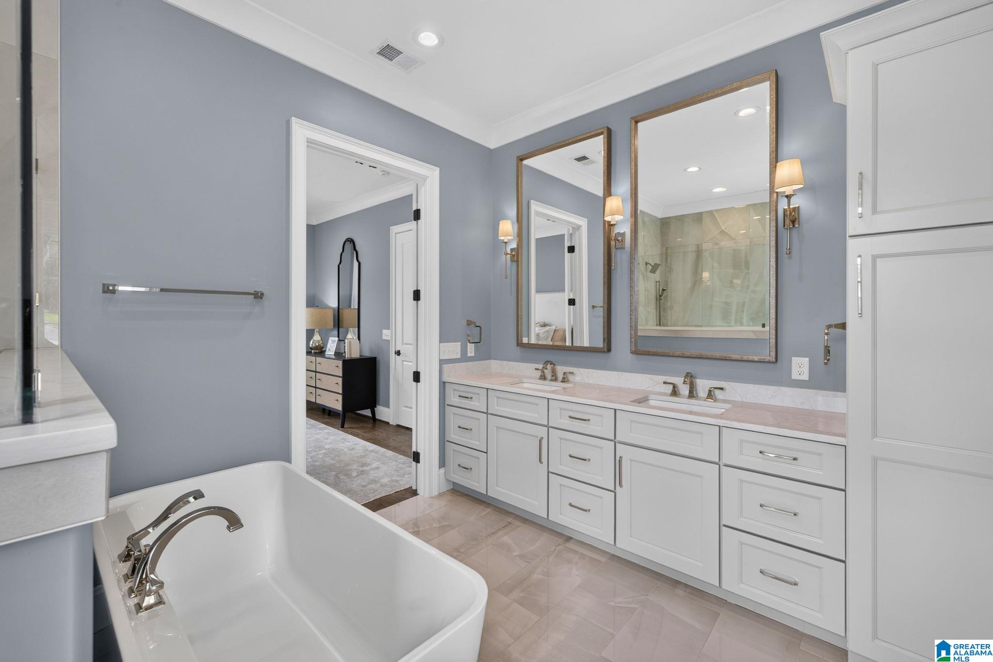 Primary bathroom with a freestanding soaking tub, double vanity, large framed mirrors, and glass-enclosed shower.