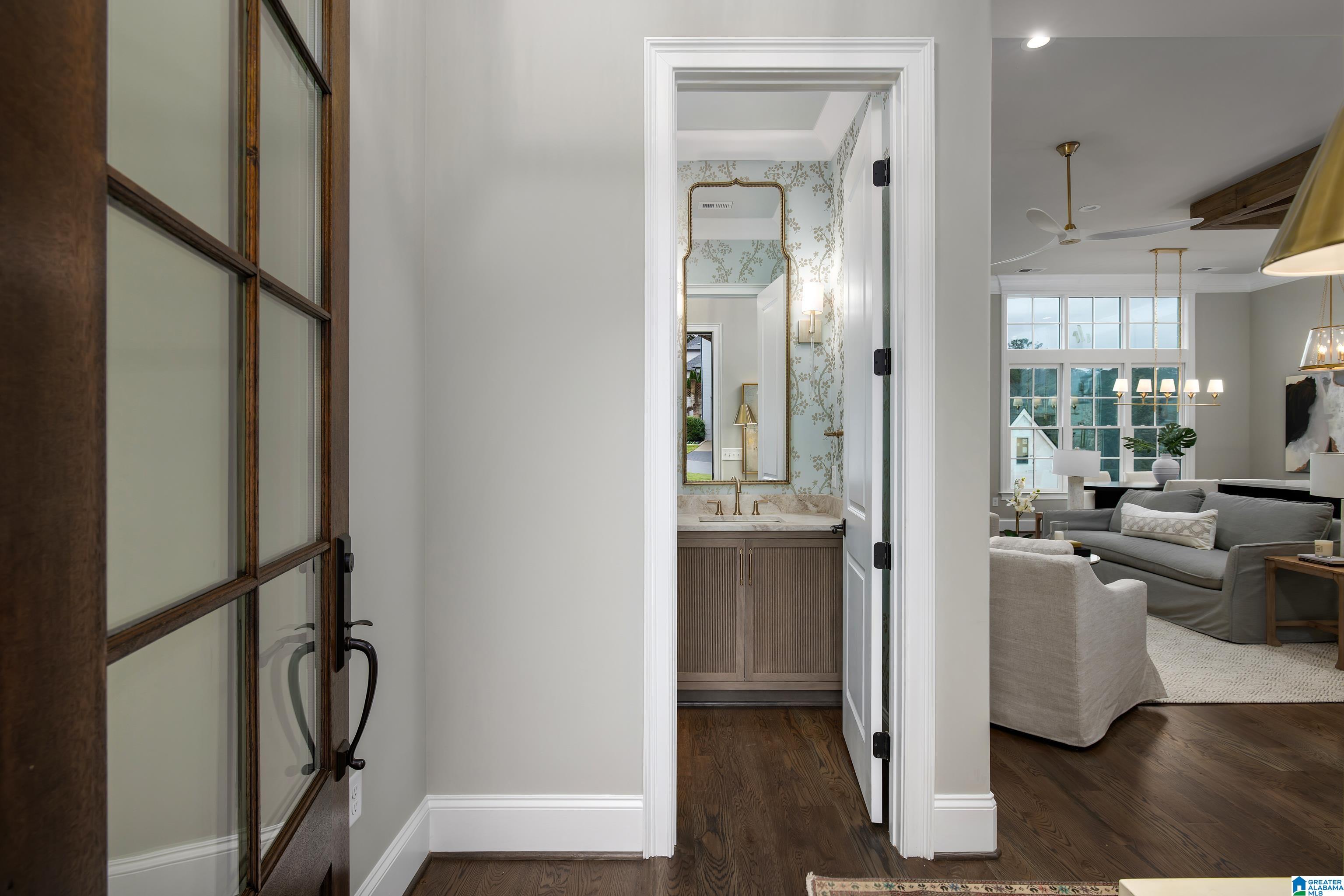 Entryway with a floral-wallpapered powder room and a bright living room beyond.