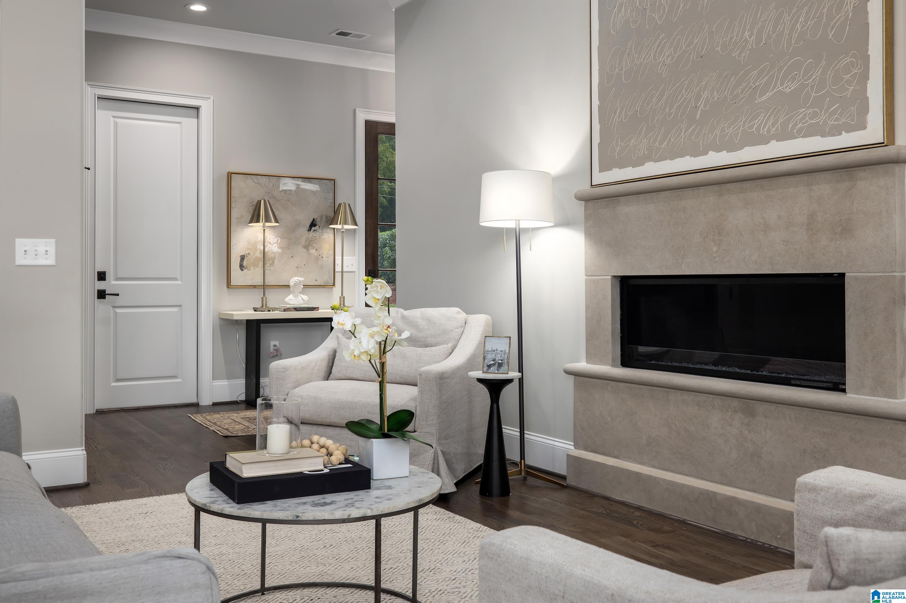 Staged living room with a stone fireplace, pale seating, and a marble coffee table.