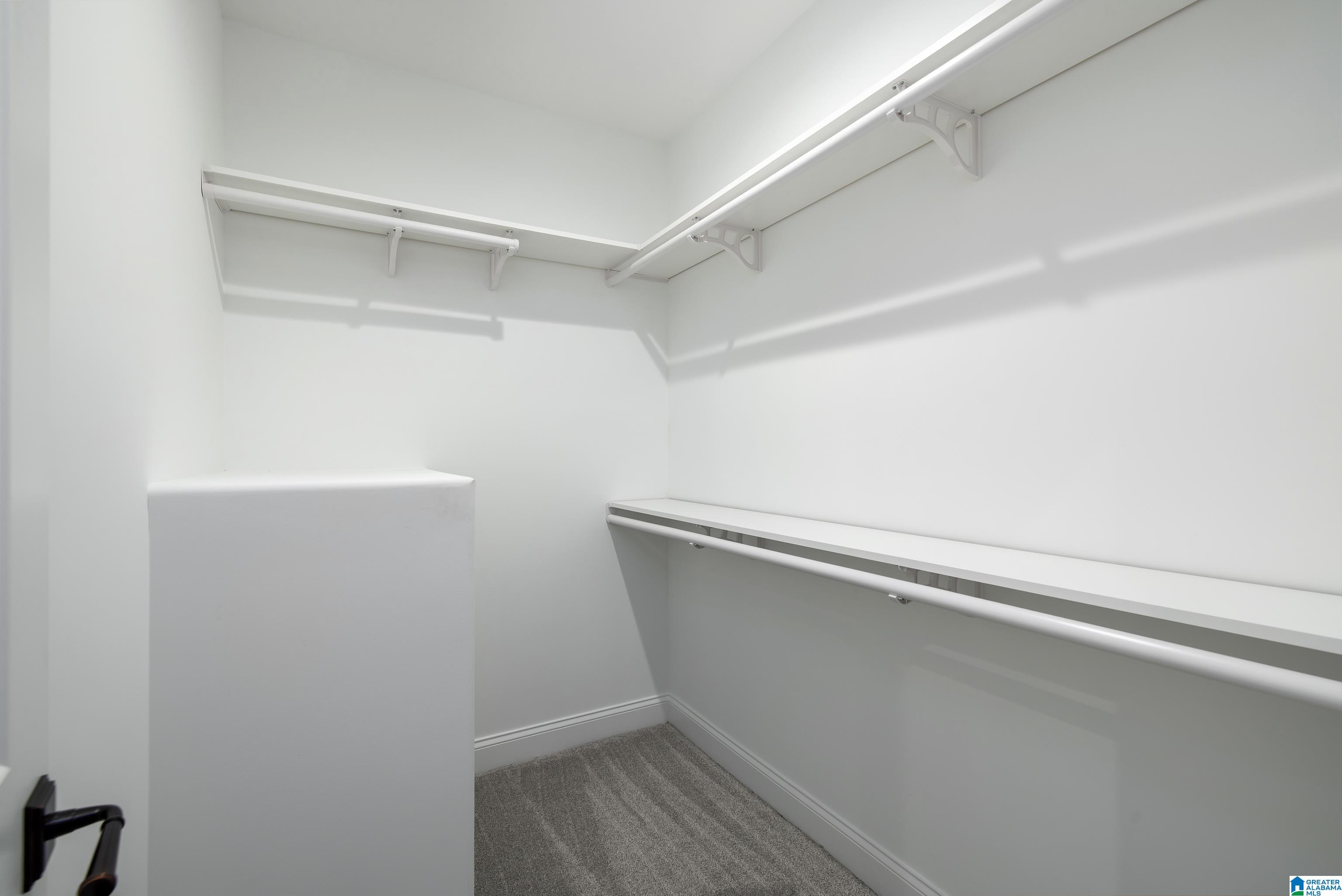 Walk-in closet with built-in shelves and hanging rods on two walls.