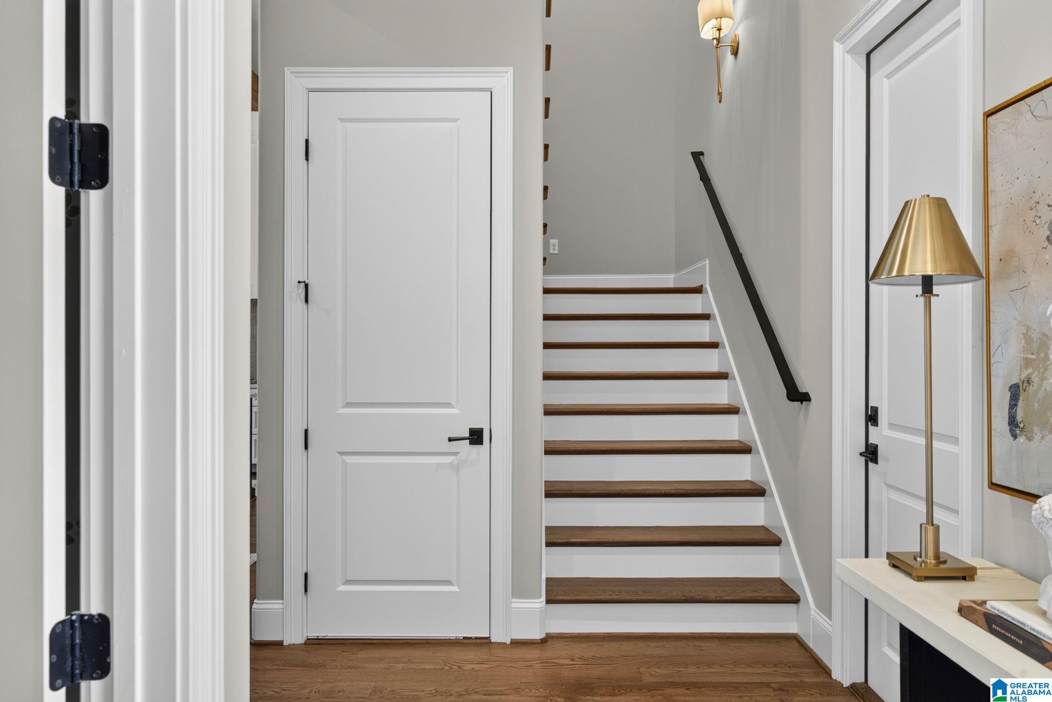 Entry hall with a staircase featuring dark wood treads, white risers, and a black handrail.