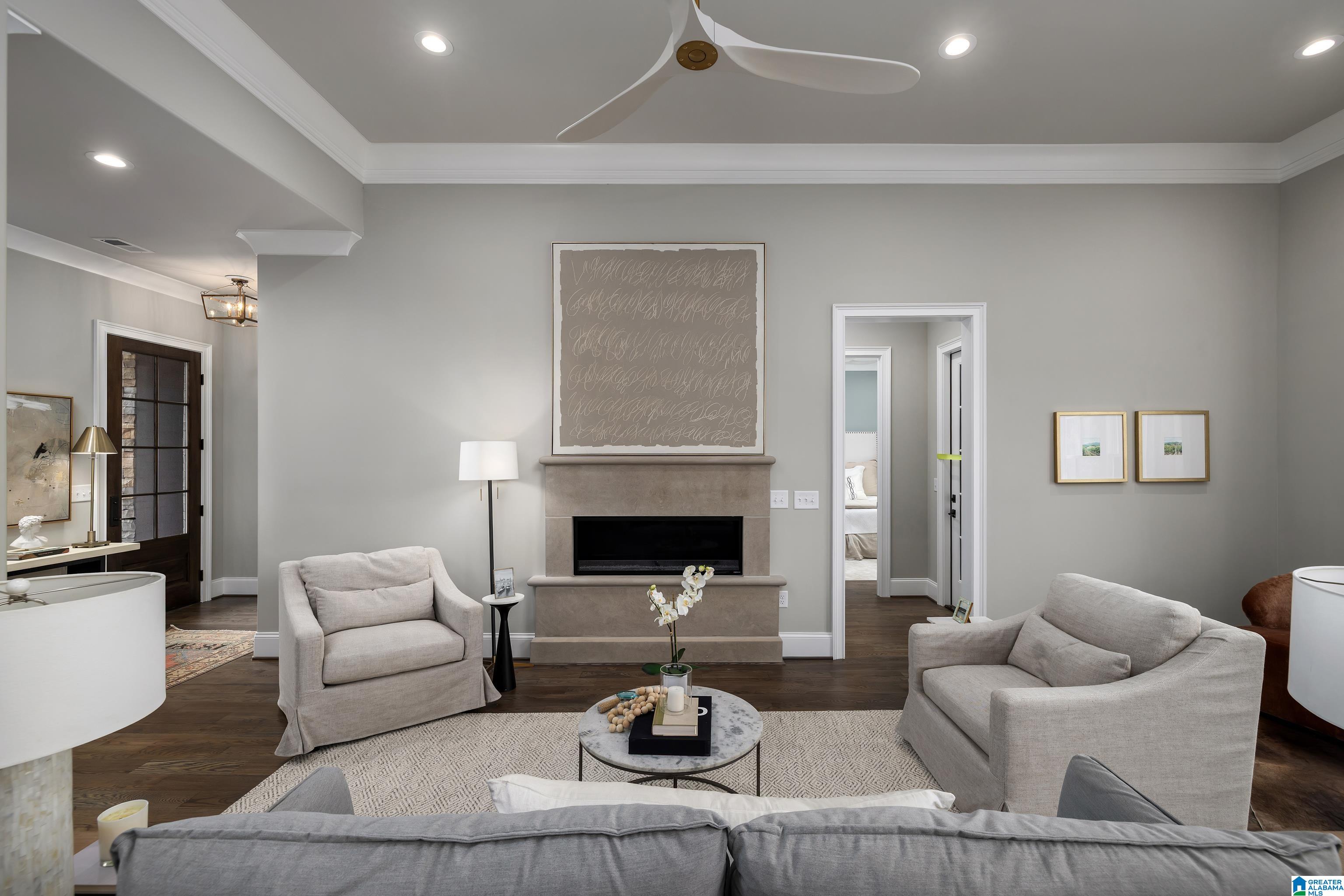 Staged living room with gray sofas, a stone fireplace, and dark hardwood floors.