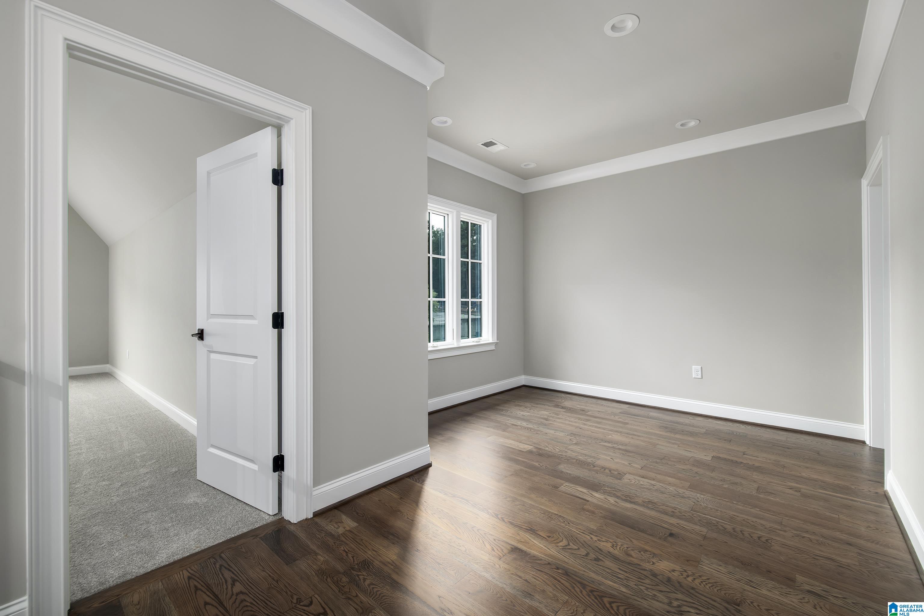 Empty gray room with dark wood floors, a tray ceiling, and paired windows.