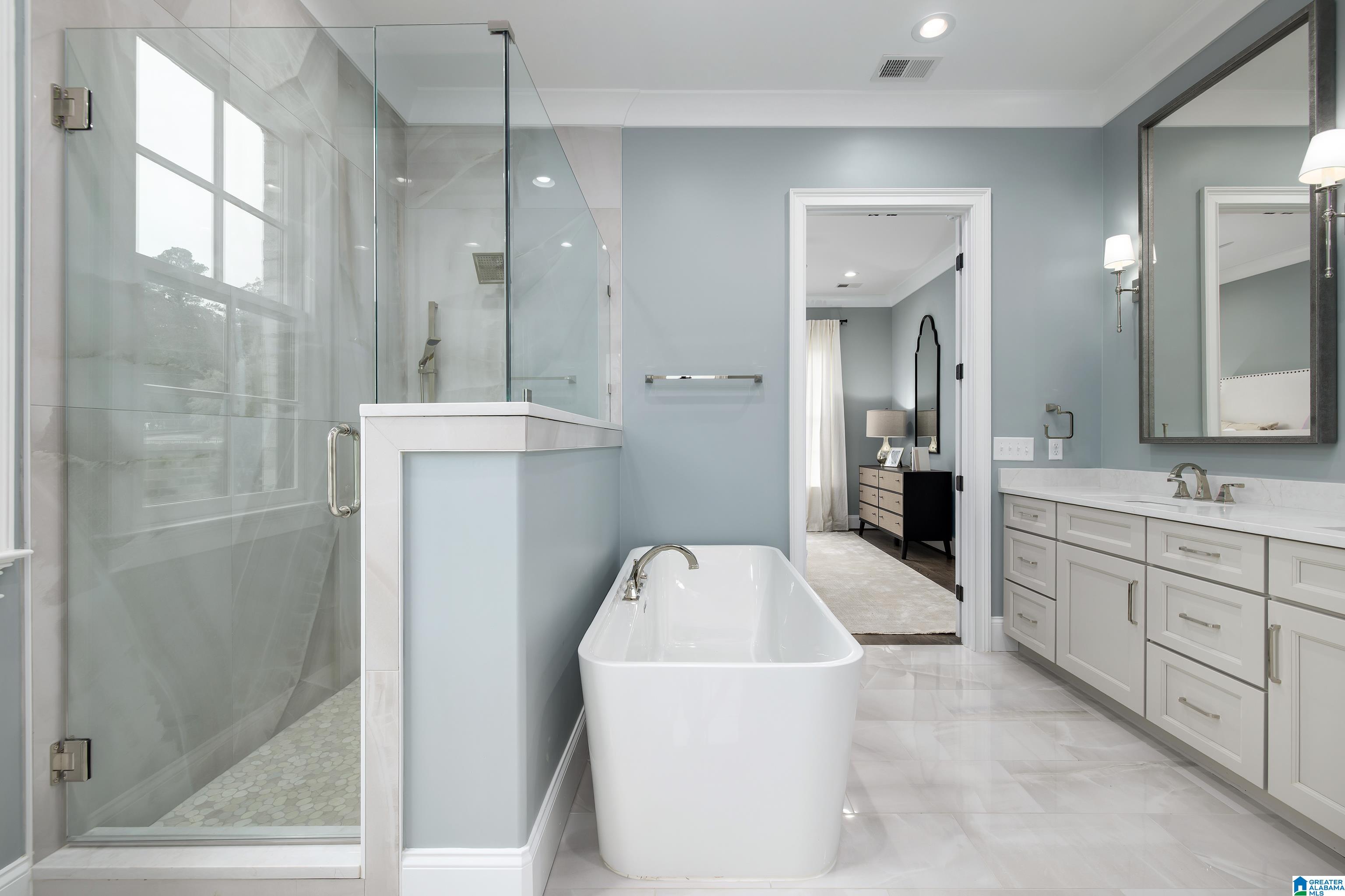 Bathroom with a freestanding soaking tub, glass shower, and white vanity.