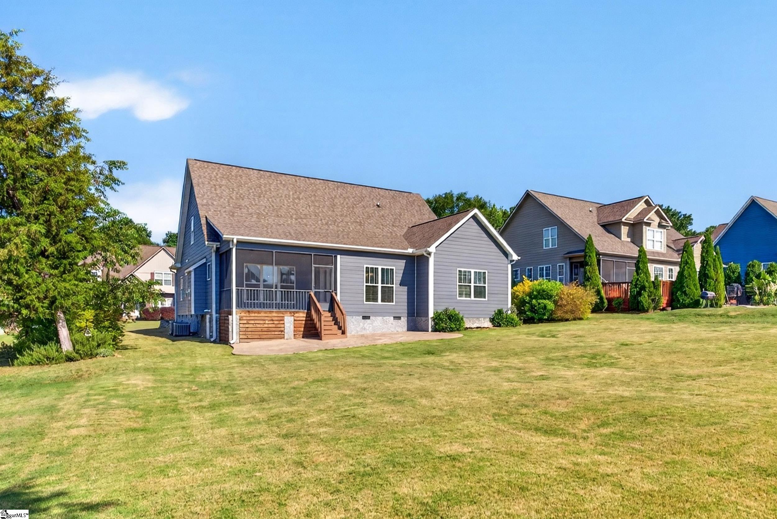 Gray house with a screened rear porch and wooden steps overlooking a broad lawn.