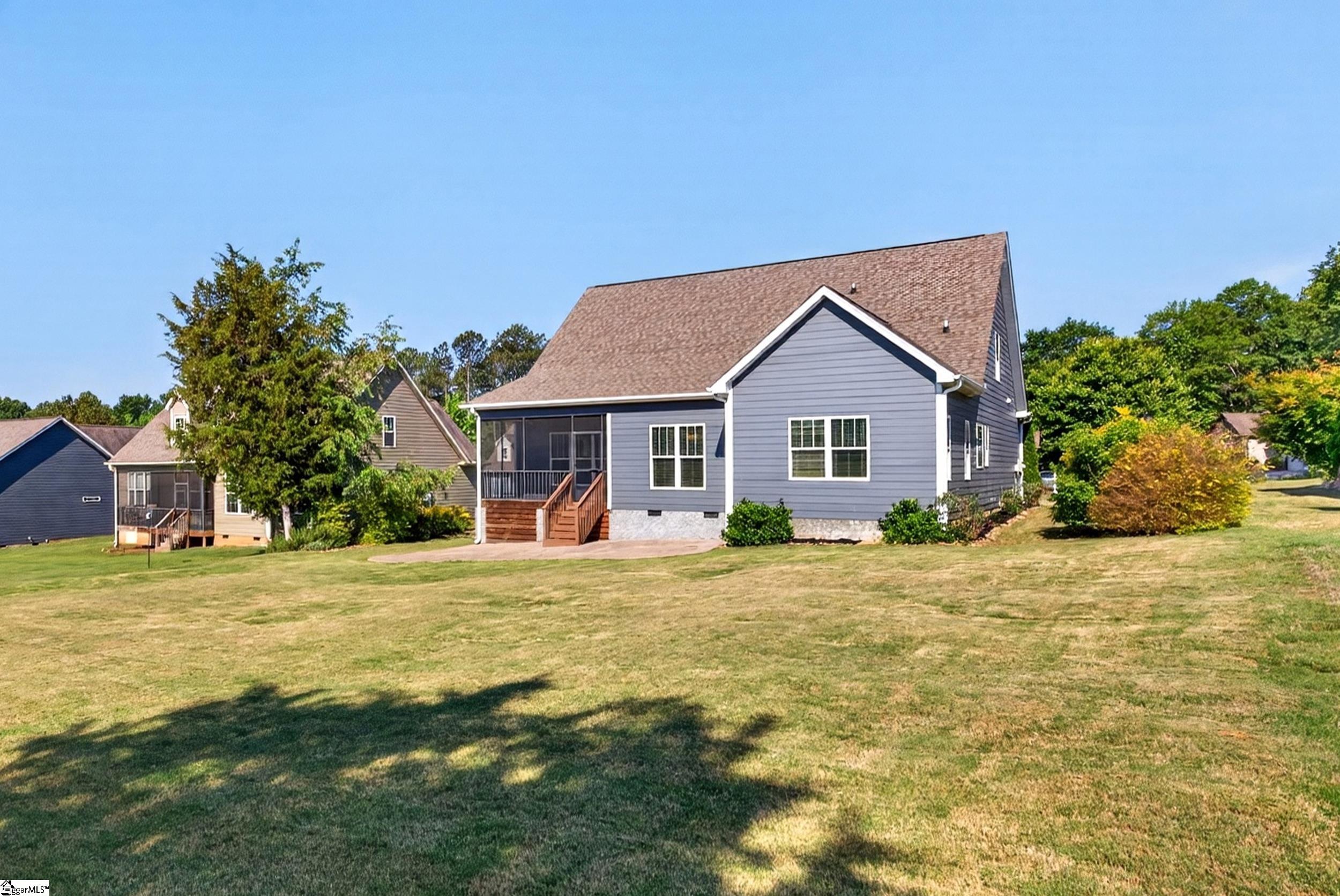 Gray house with a screened porch and wooden steps above a broad lawn.