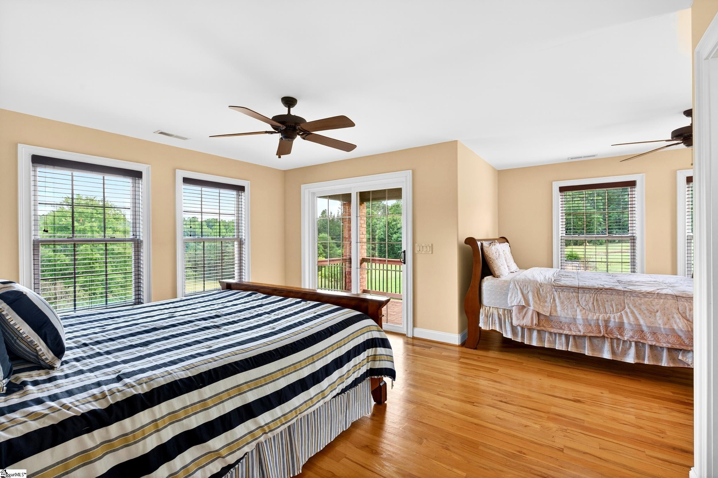 Bedroom with two beds, hardwood floors, and a sliding glass door opening onto a balcony.