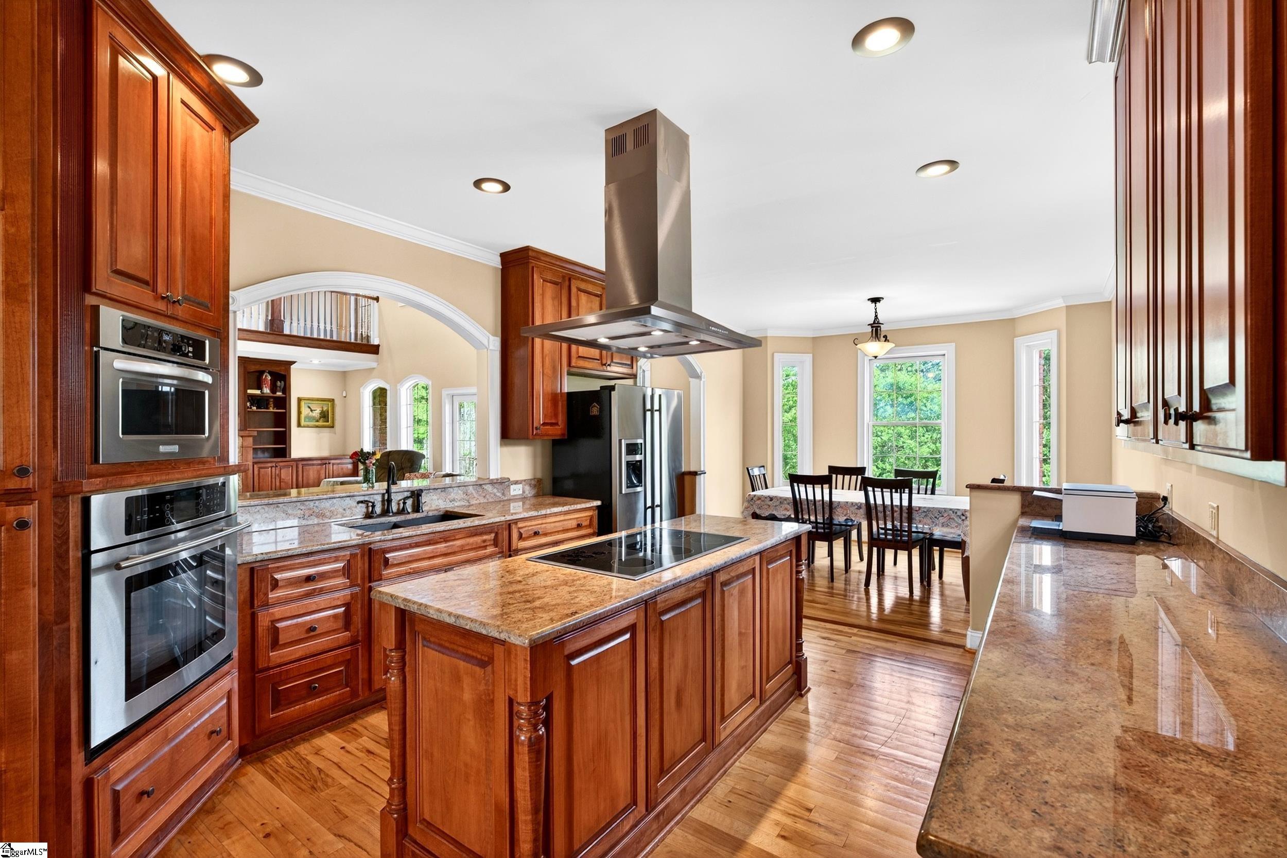 Kitchen with wood cabinetry, granite counters, a central island, and an adjoining dining area.