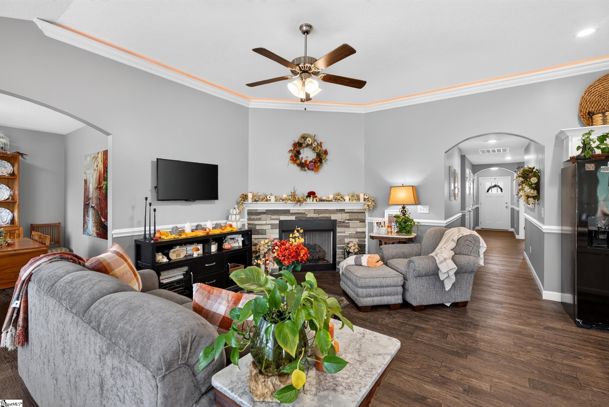 Living room with a stone fireplace, gray seating, and a tray ceiling with accent lighting.