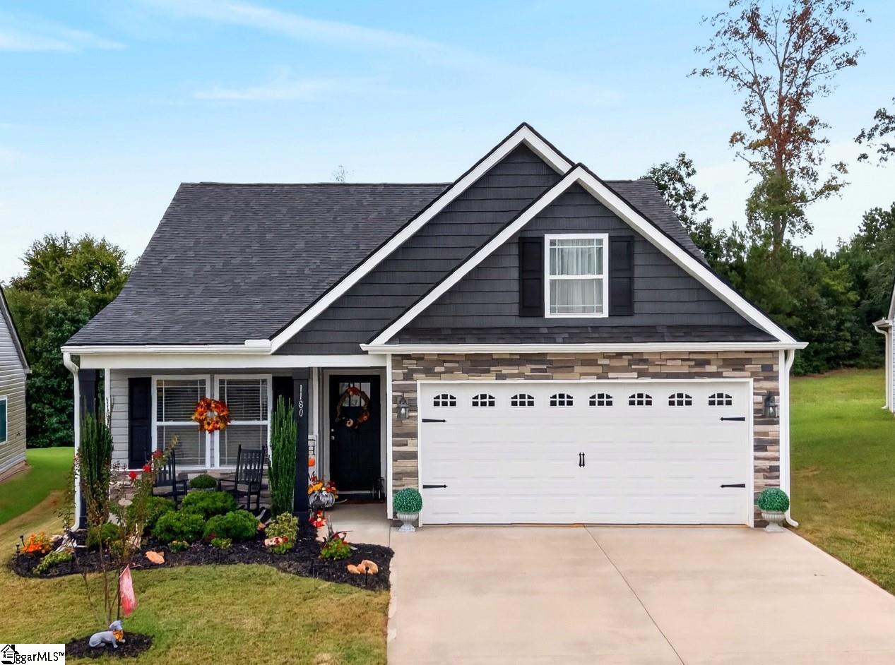 Dark gray gabled house with stone facade, white two-car garage, and landscaped front entry.