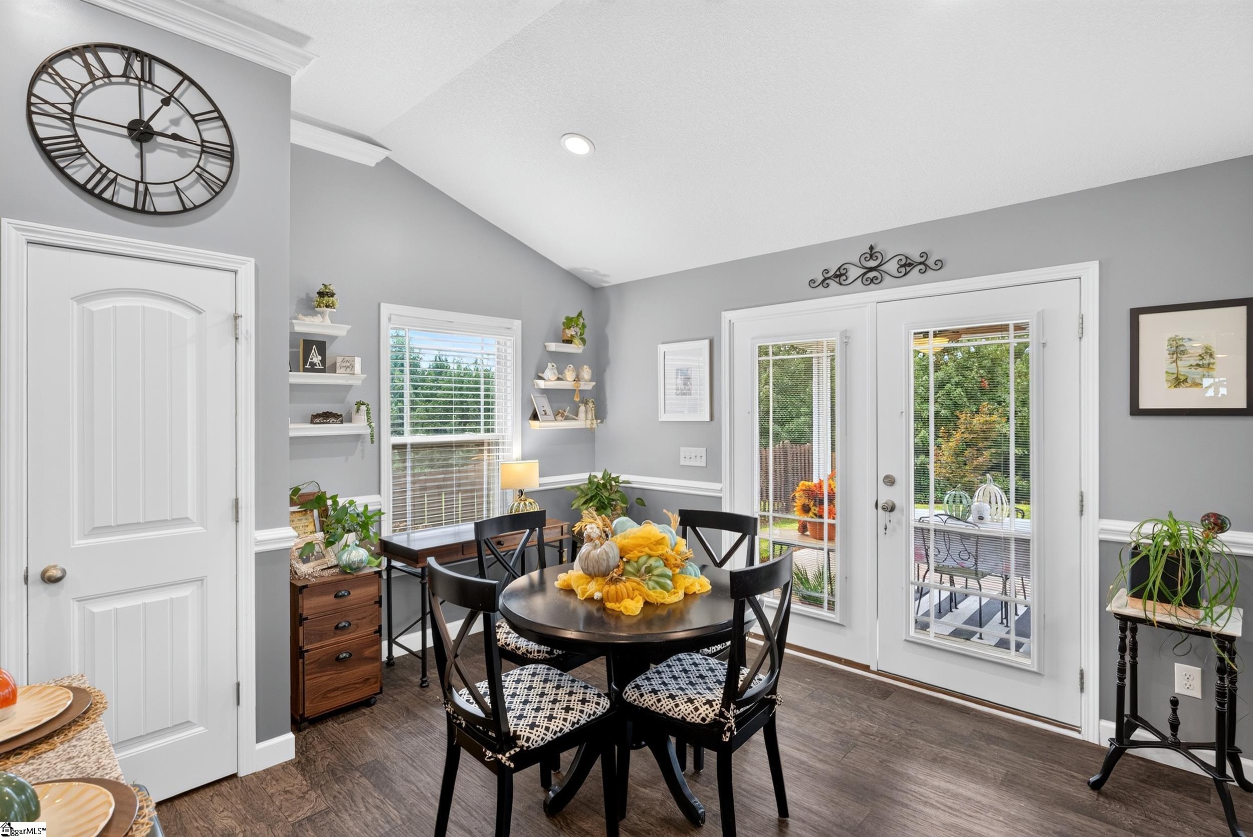 Dining area with a round table, patterned chairs, and glazed doors opening to a patio.