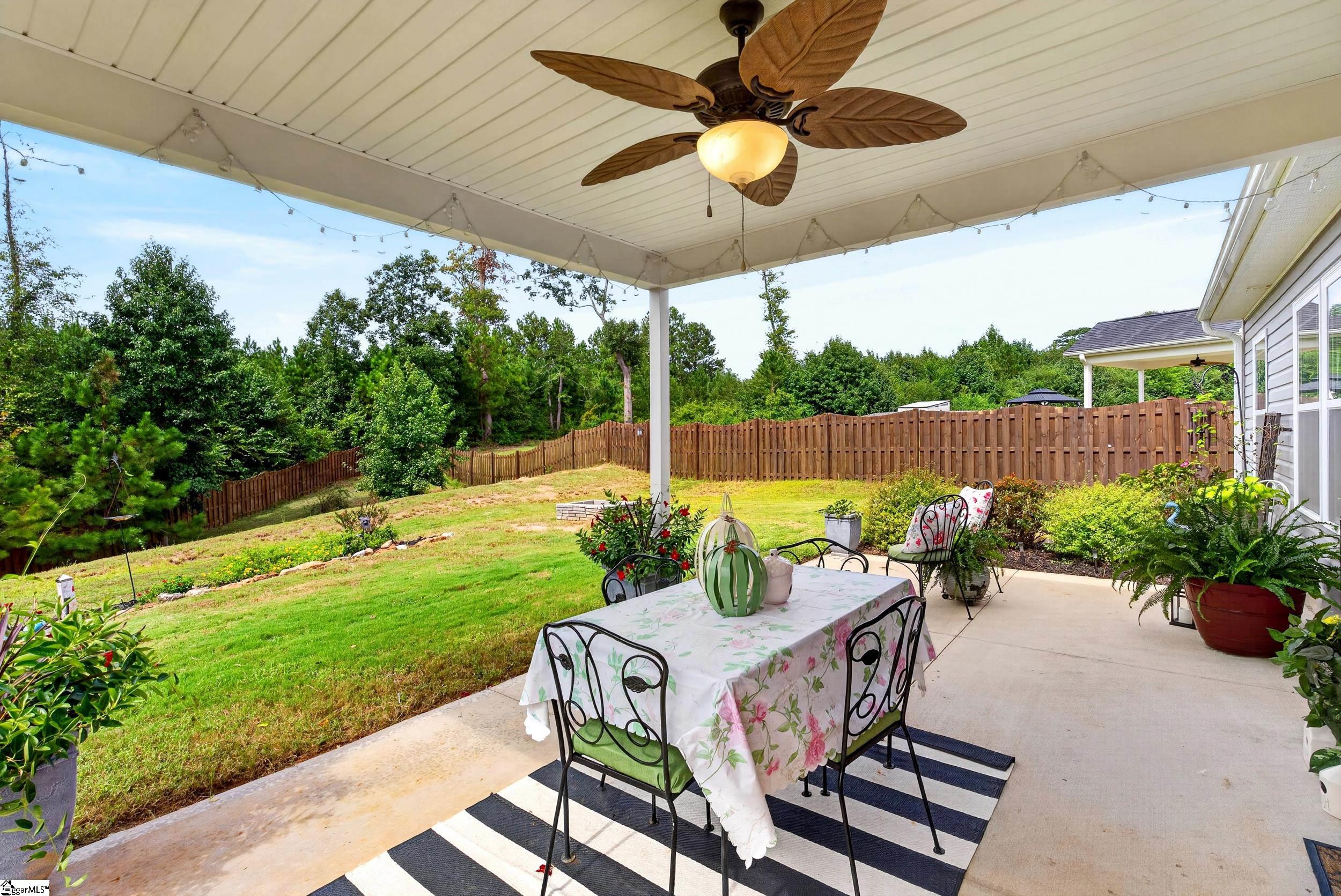 Covered patio with a dining set overlooking a fenced, tree-lined backyard.