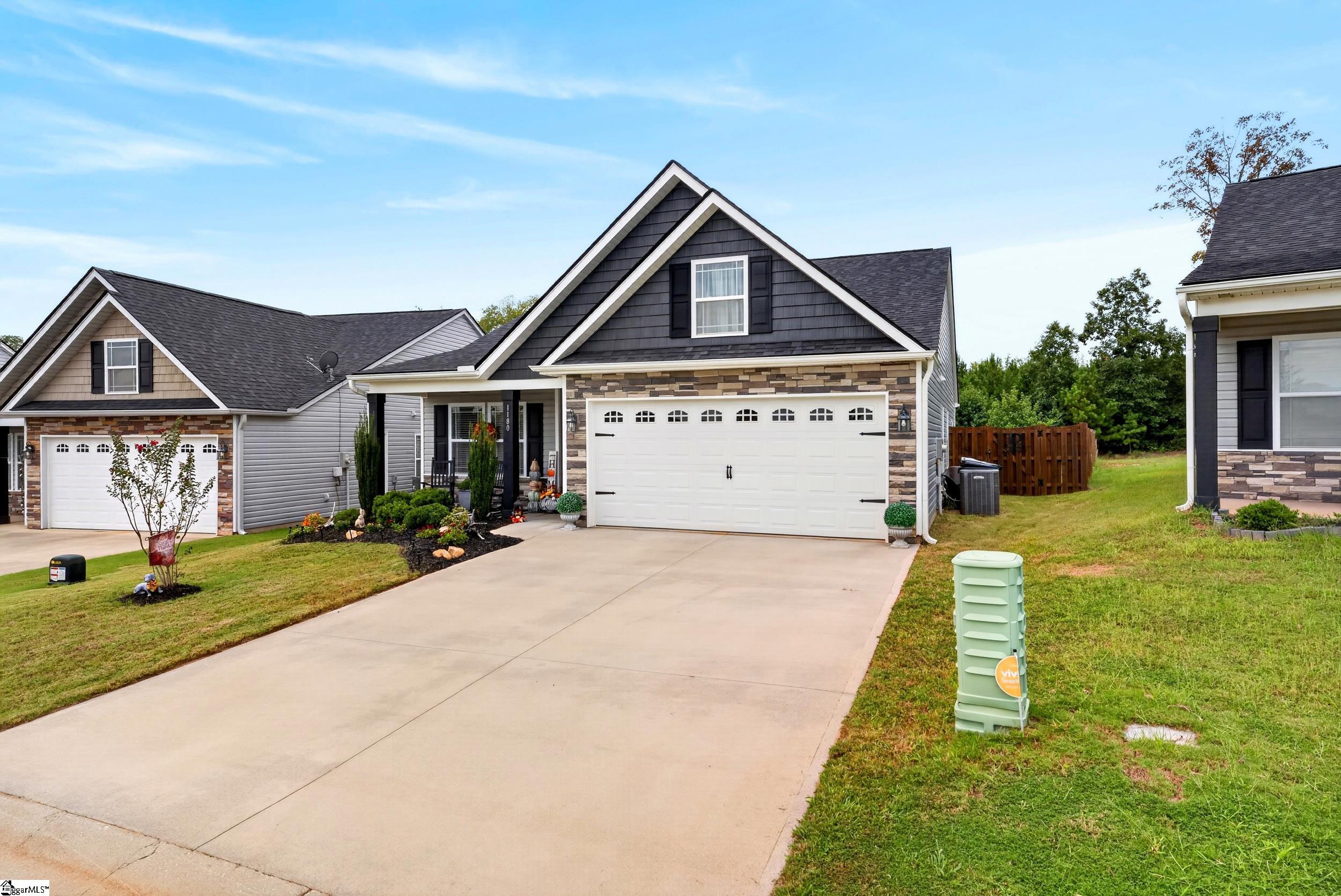 Two-story charcoal-and-stone house with a white double garage and wide concrete driveway.