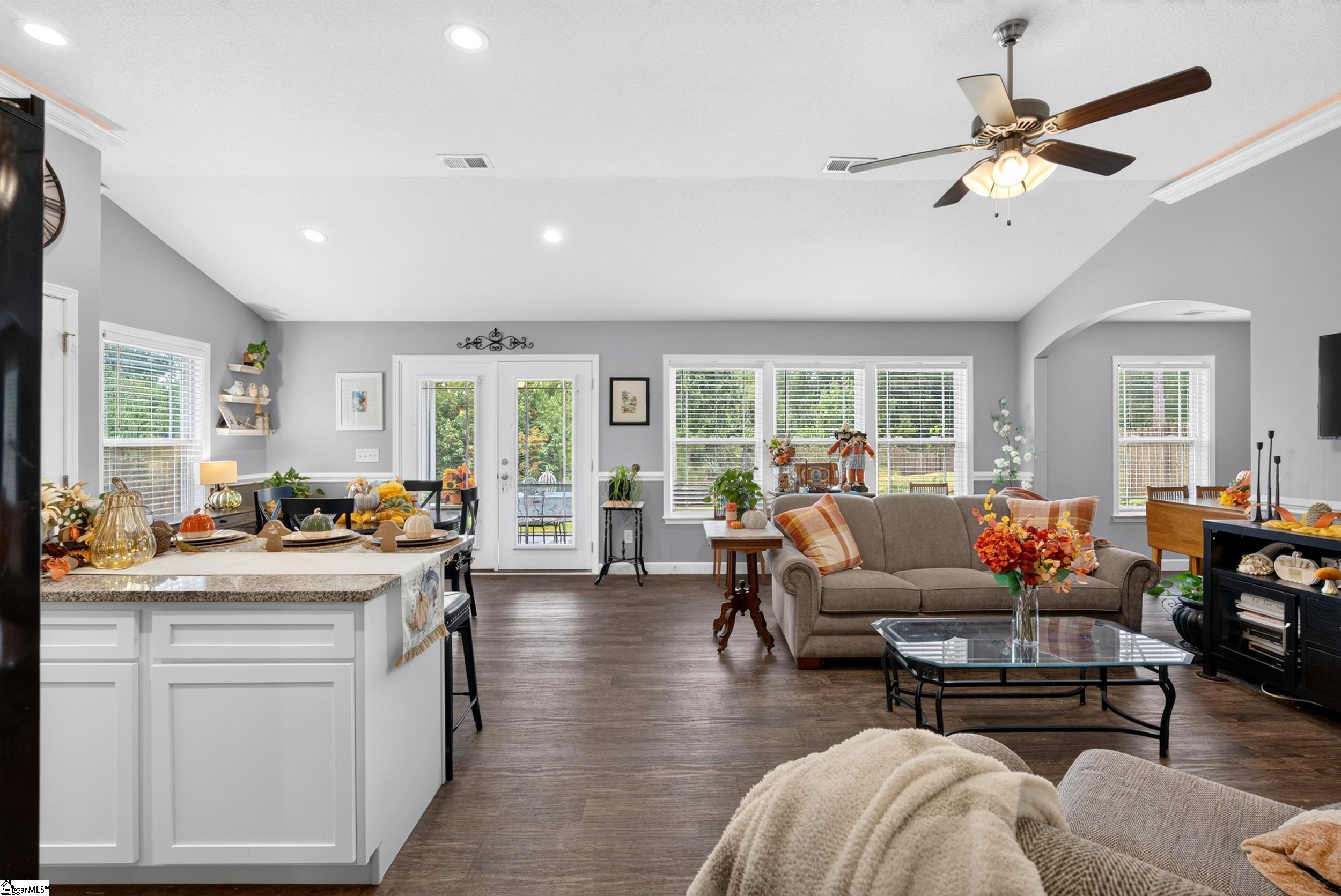 Open living room and kitchen with a white island, gray walls, and autumn decorations.