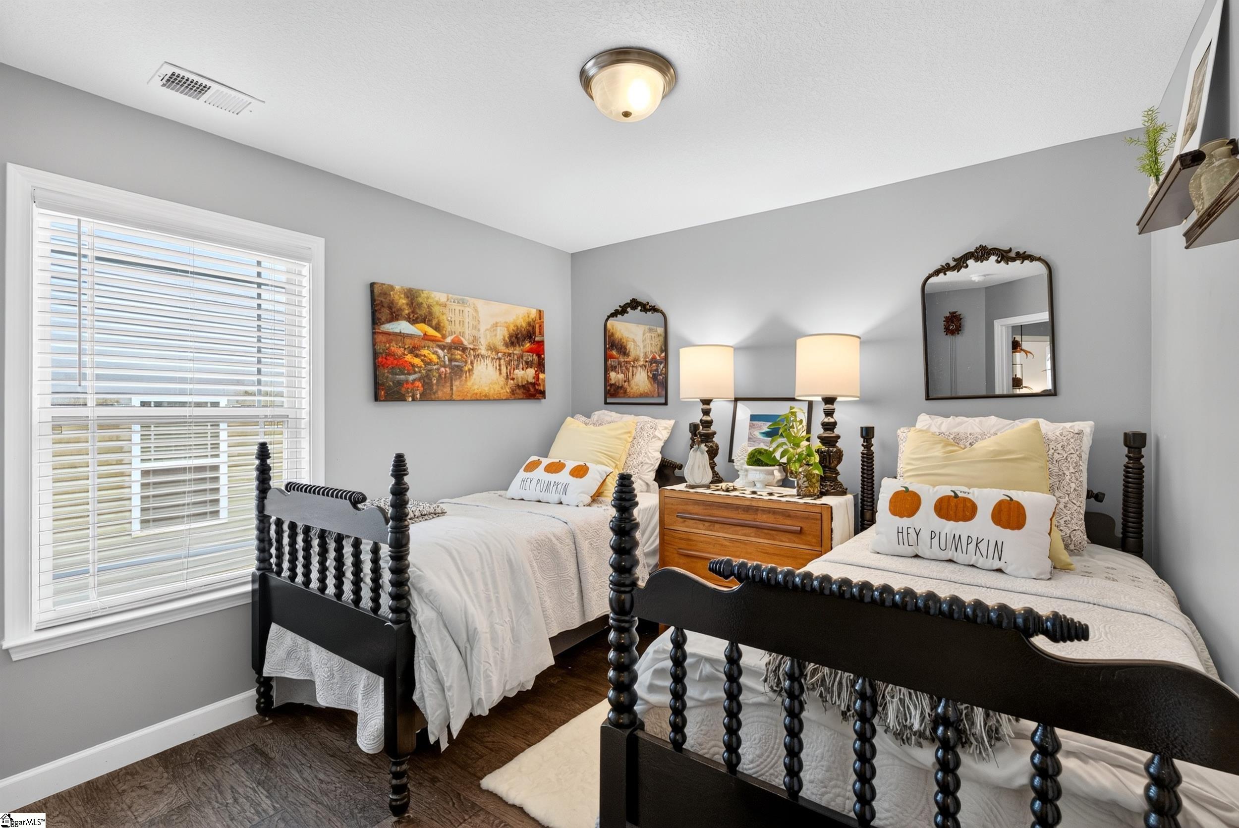 Bedroom with two black spindle beds, pumpkin-print pillows, and a shared wooden nightstand.