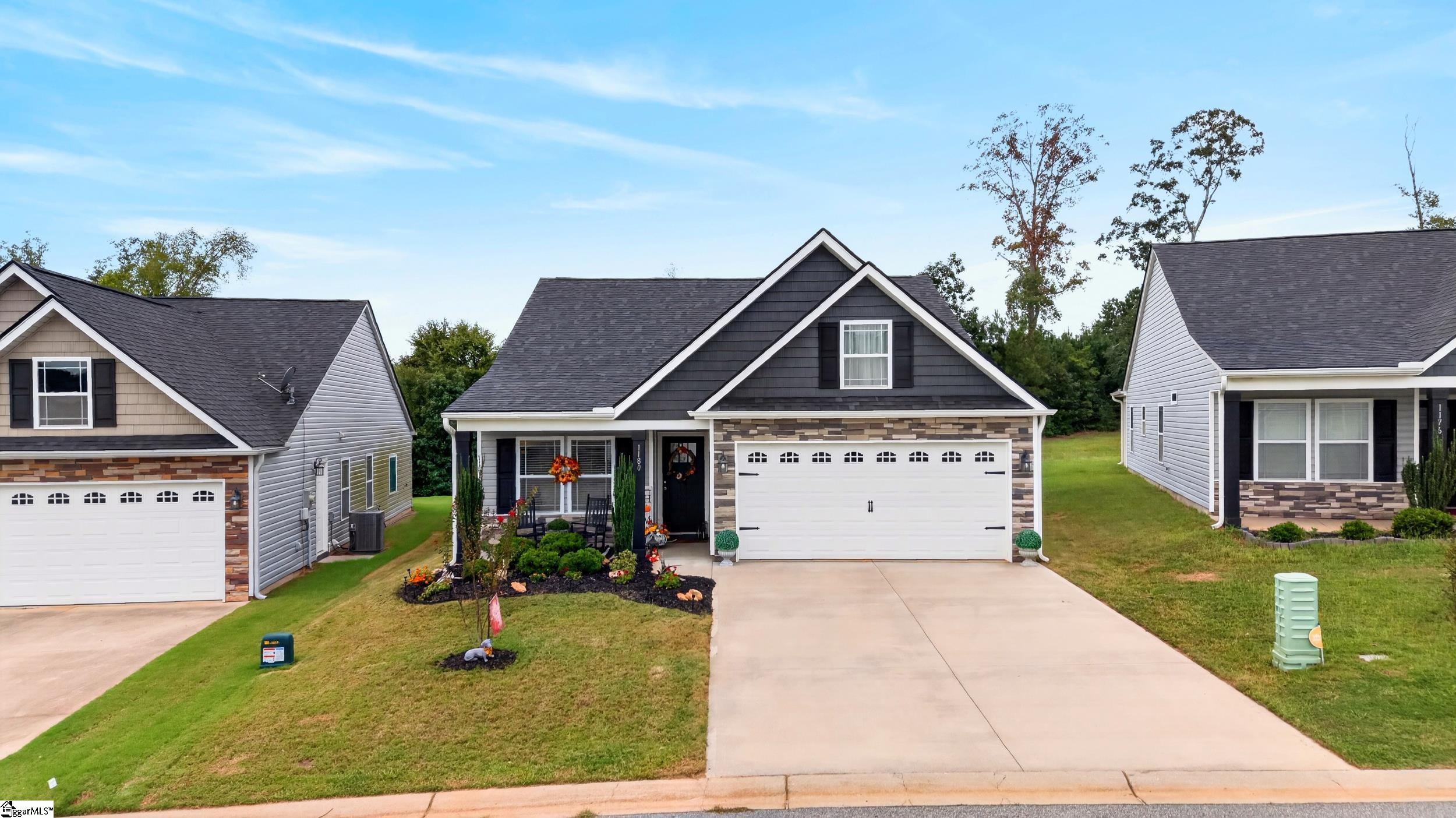Dark gray gabled home with stone accents, a white two-car garage, and a wide driveway.