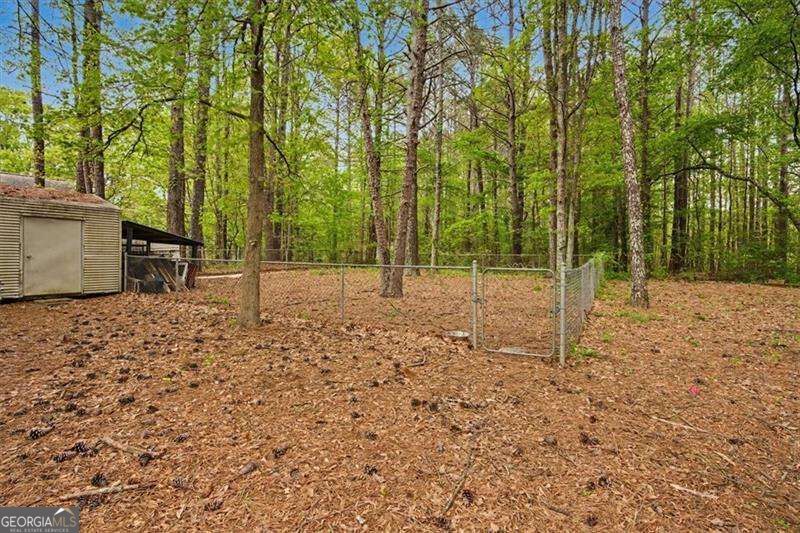 Wooded backyard with a chain-link fenced area and storage shed.