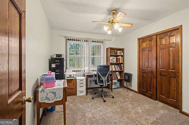 Home office with a bookcase, desk, carpeted floor, and dark wood doors.