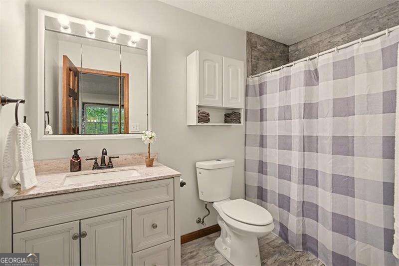 Bathroom with a white paneled vanity and gray-and-white checkered shower curtain.