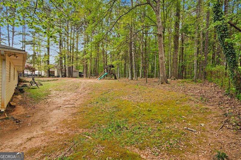 Wooded backyard with a small playset and part of the house visible at left.