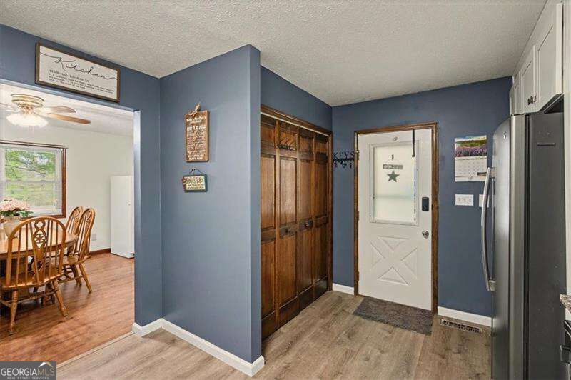 Entryway with blue walls, built-in wooden cabinets, white front door, and adjoining dining room.