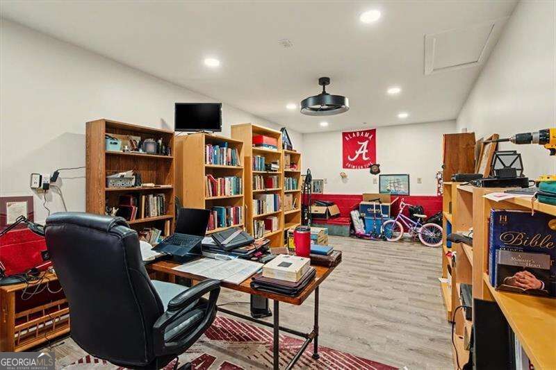 Furnished office with wooden bookshelves, a desk, and Alabama memorabilia.