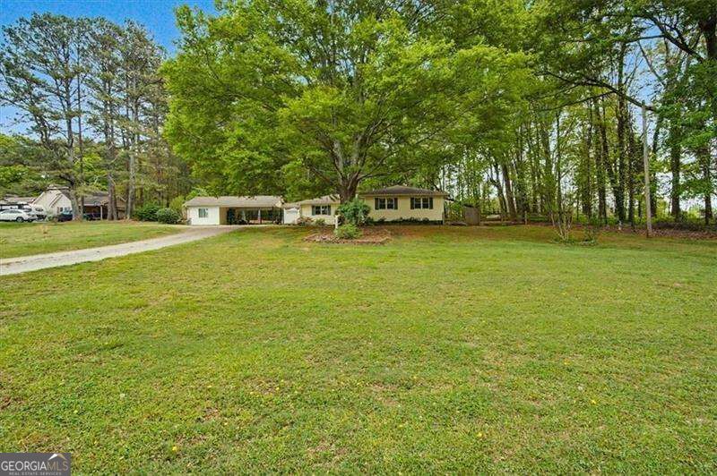 Single-story home beyond a broad lawn, framed by mature trees and a curving driveway.