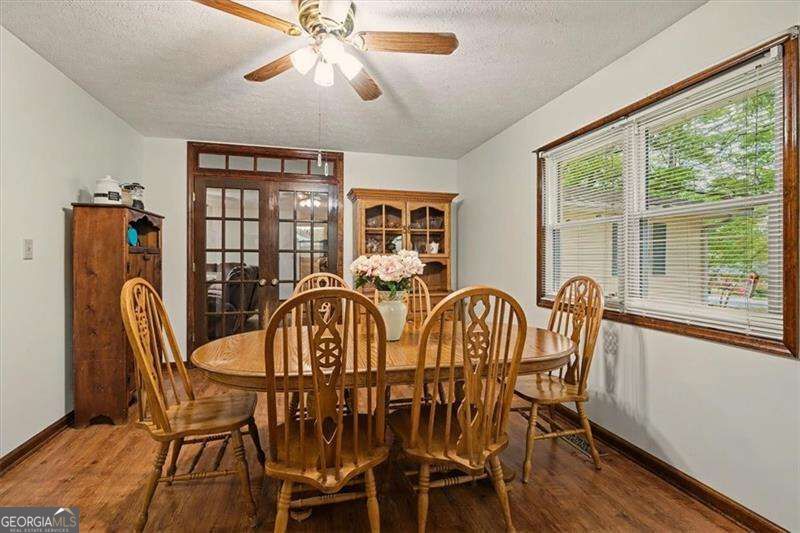 Dining room with a round wooden table, carved chairs, china cabinets, and a large window.