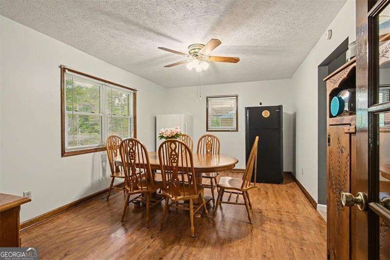 Dining room with a round wooden table, carved chairs, hardwood floors, and a black refrigerator.