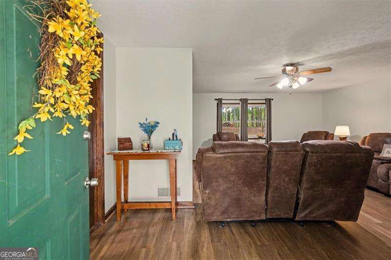 Furnished living room with brown recliners, a green front door, and wood-look flooring.