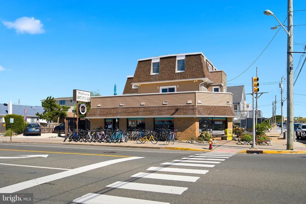 Corner bicycle shop with rows of bicycles outside and a crosswalk in front.