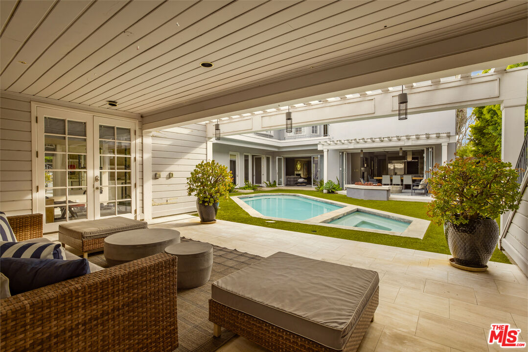 Covered patio with wicker seating overlooking a courtyard pool and spa.