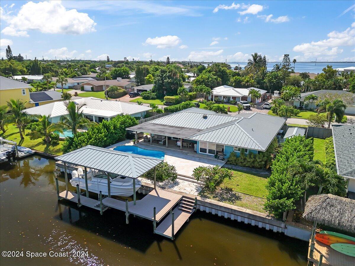 Waterfront home with a canal-side boat dock, boat, and backyard pool.
