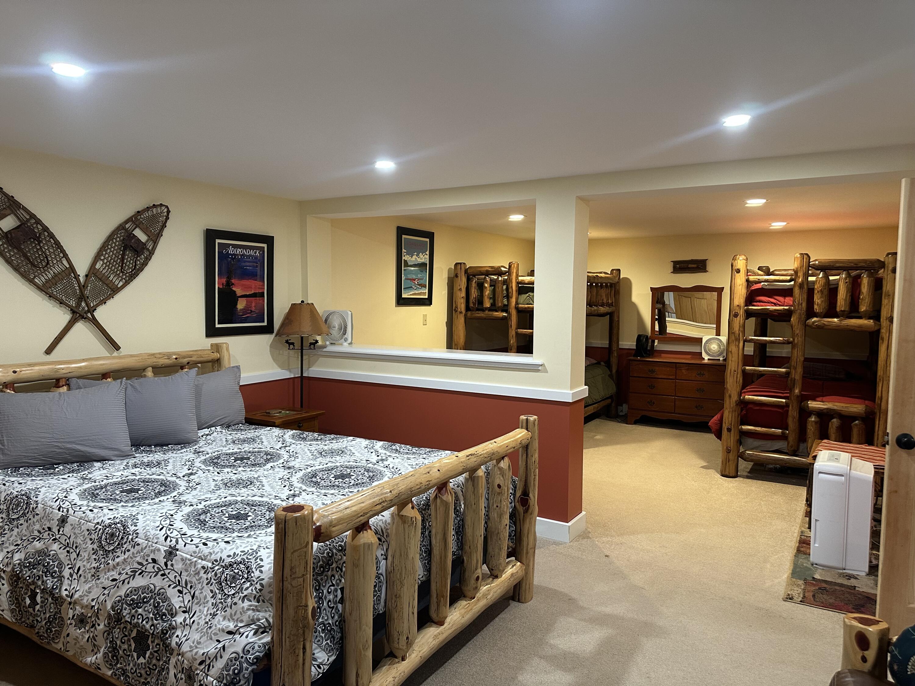 Bedroom with a rustic log-frame bed and log bunk beds in an adjoining sleeping area.