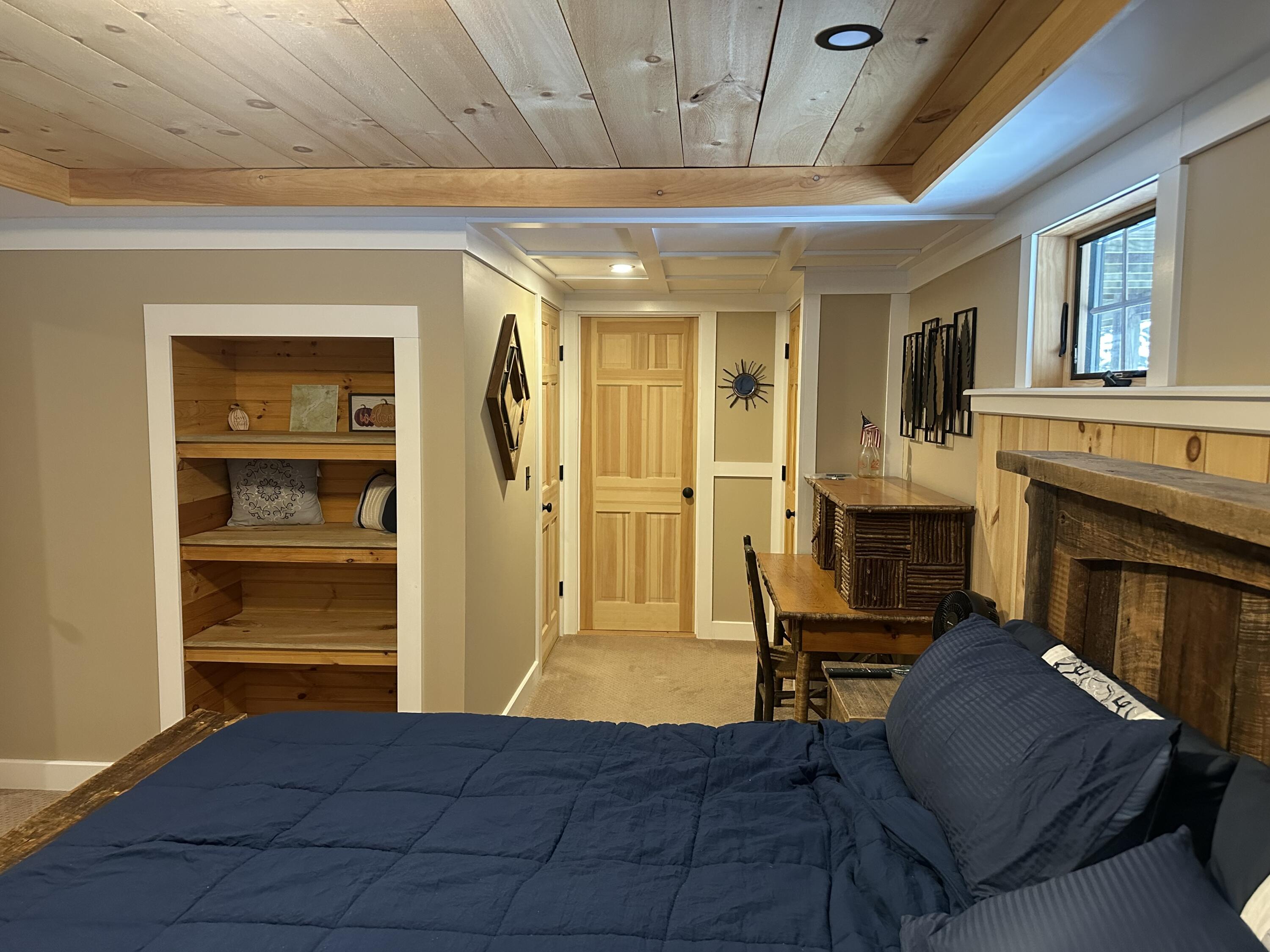 Bedroom with a navy bed, built-in wooden shelves, and a rustic wood fireplace.