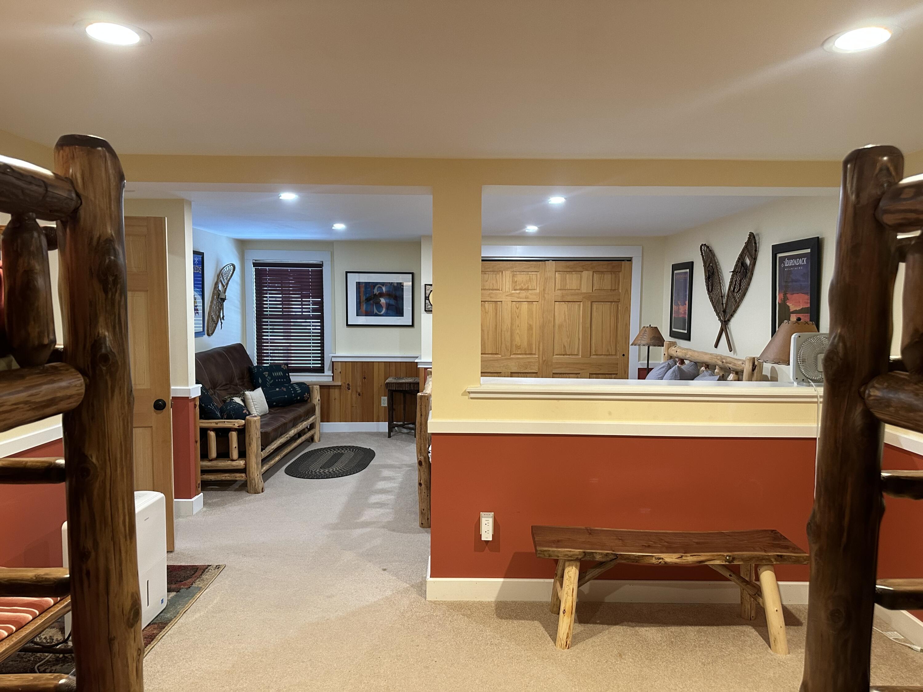 Furnished room with a log-frame sofa, wood-paneled doors, wall-mounted snowshoes, and a rustic wooden bench.
