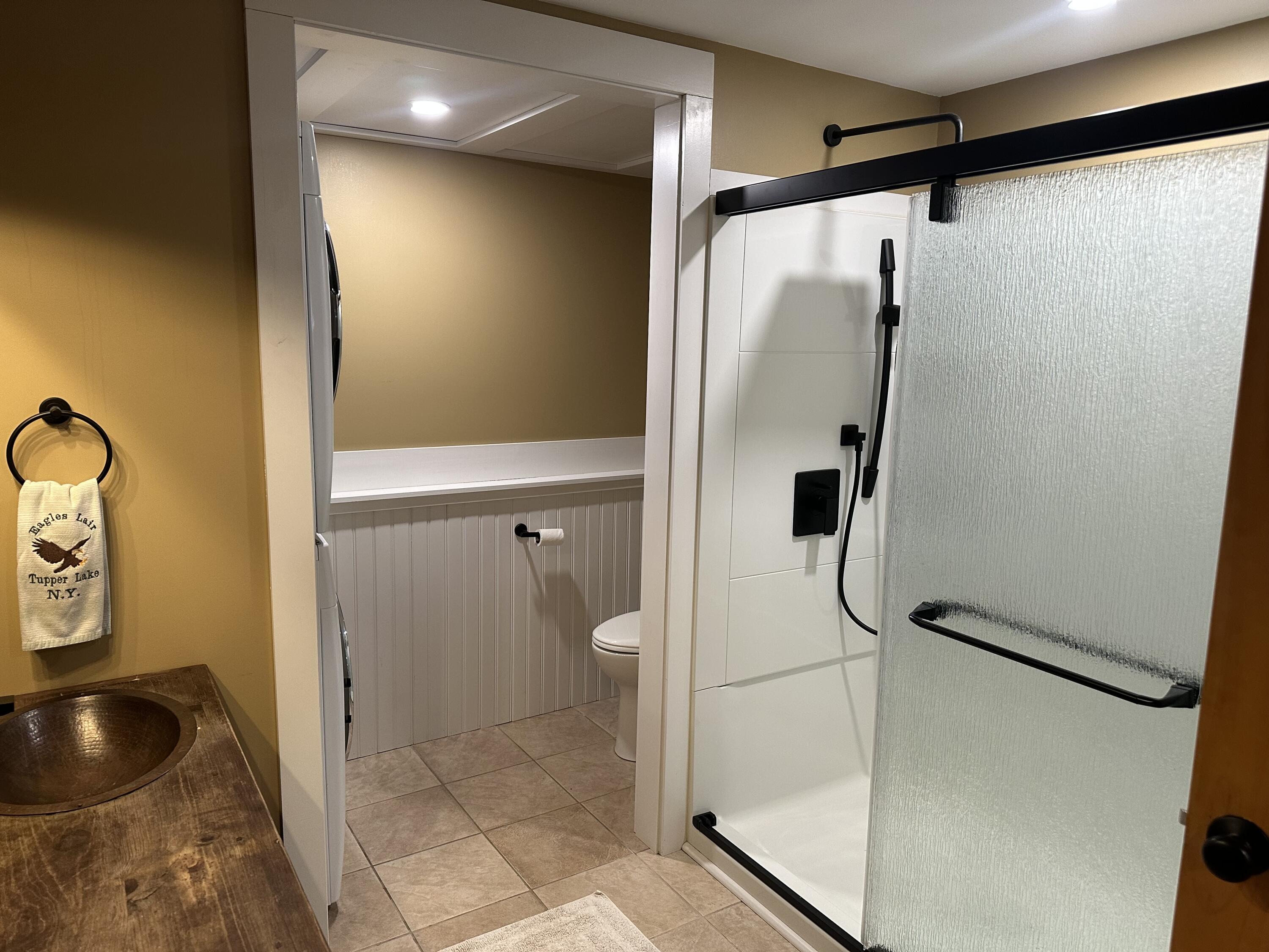 Bathroom with a glass-enclosed shower and rustic wood vanity with a hammered vessel sink.