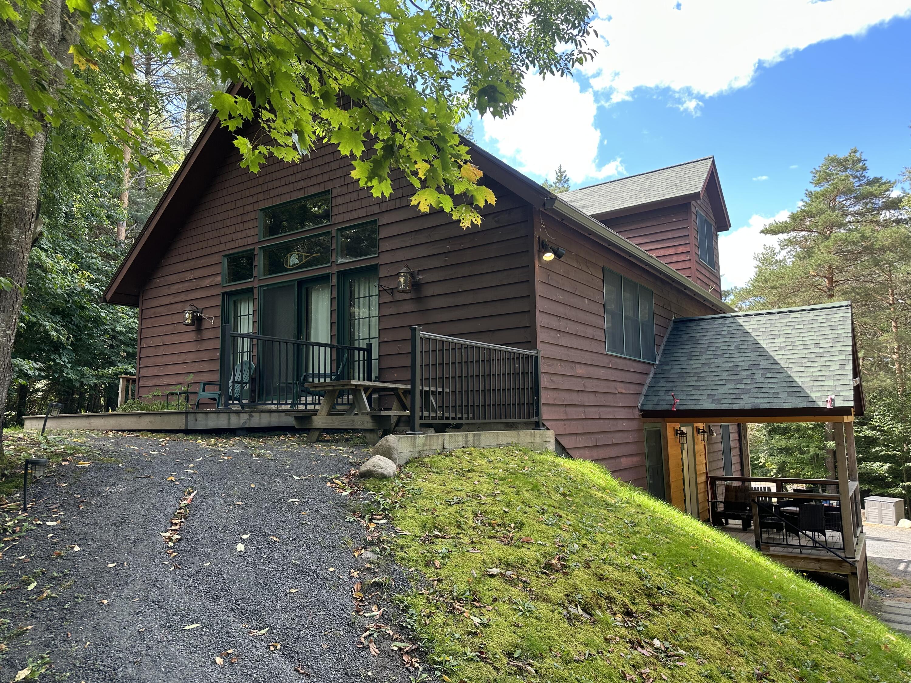 Wood-sided house with a raised deck and covered patio among trees.