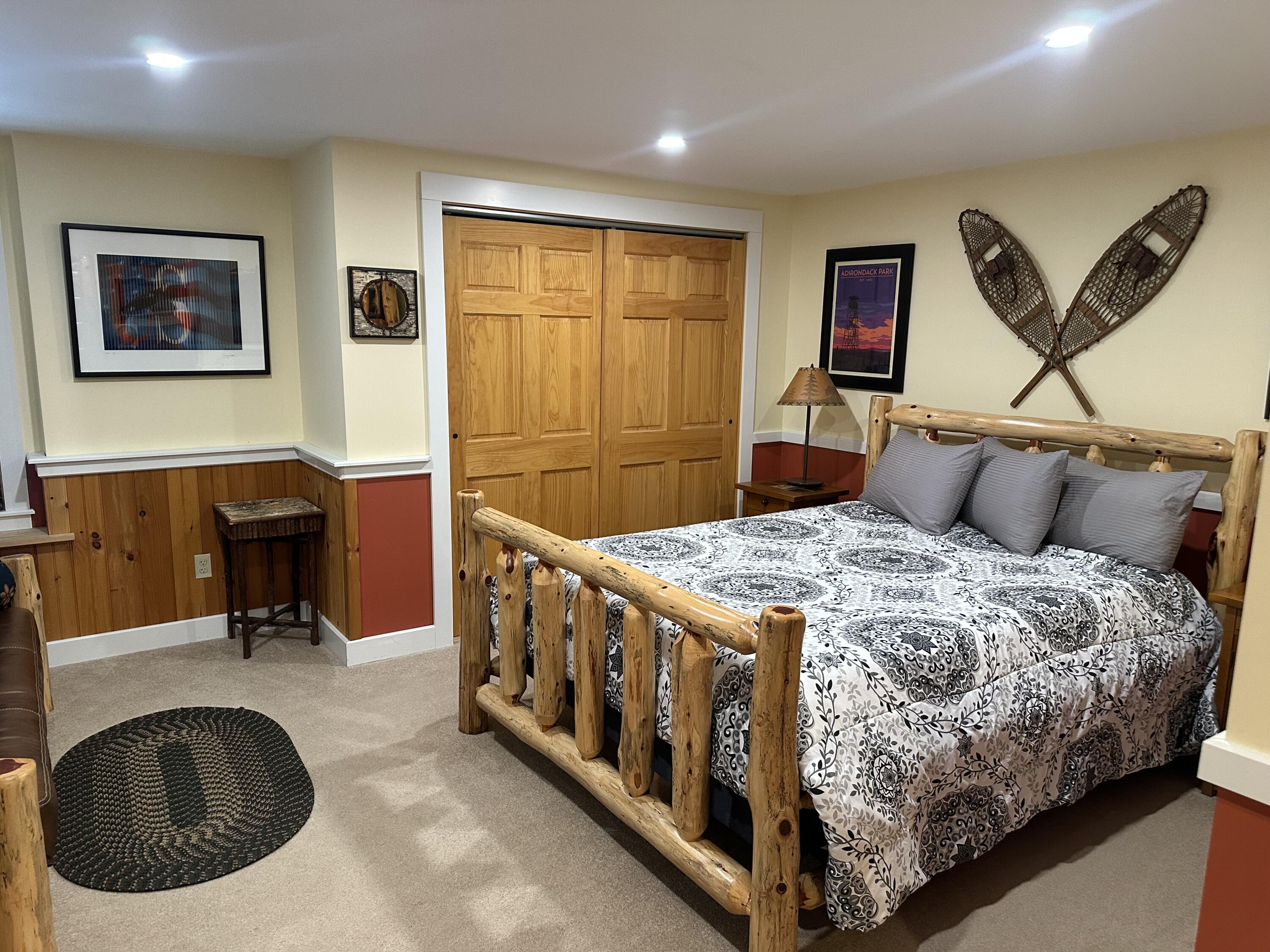 Bedroom with a rustic log-frame bed and crossed snowshoes mounted above it.