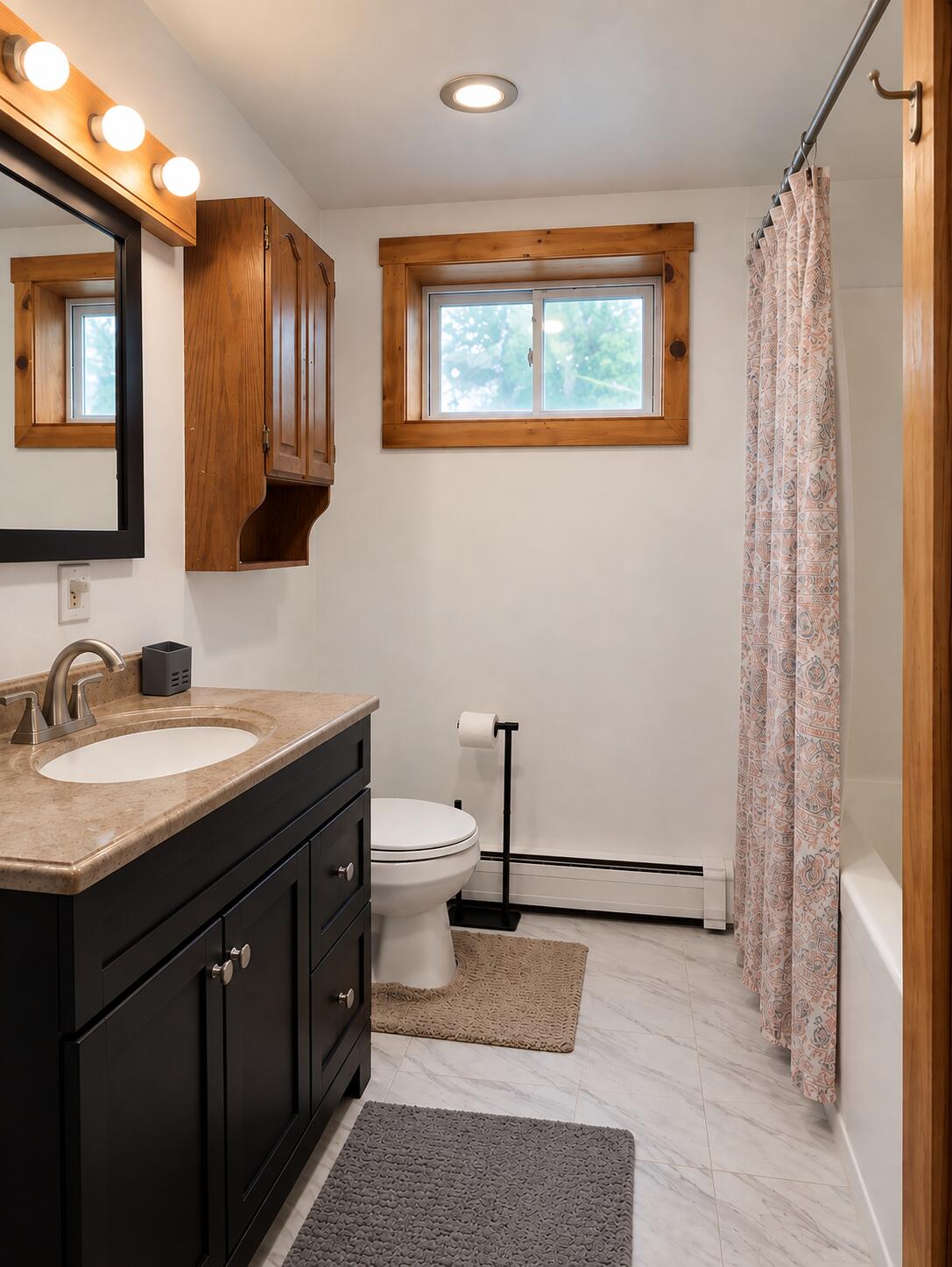 Bathroom with a dark wood vanity, marble-look surfaces, and a patterned shower curtain.
