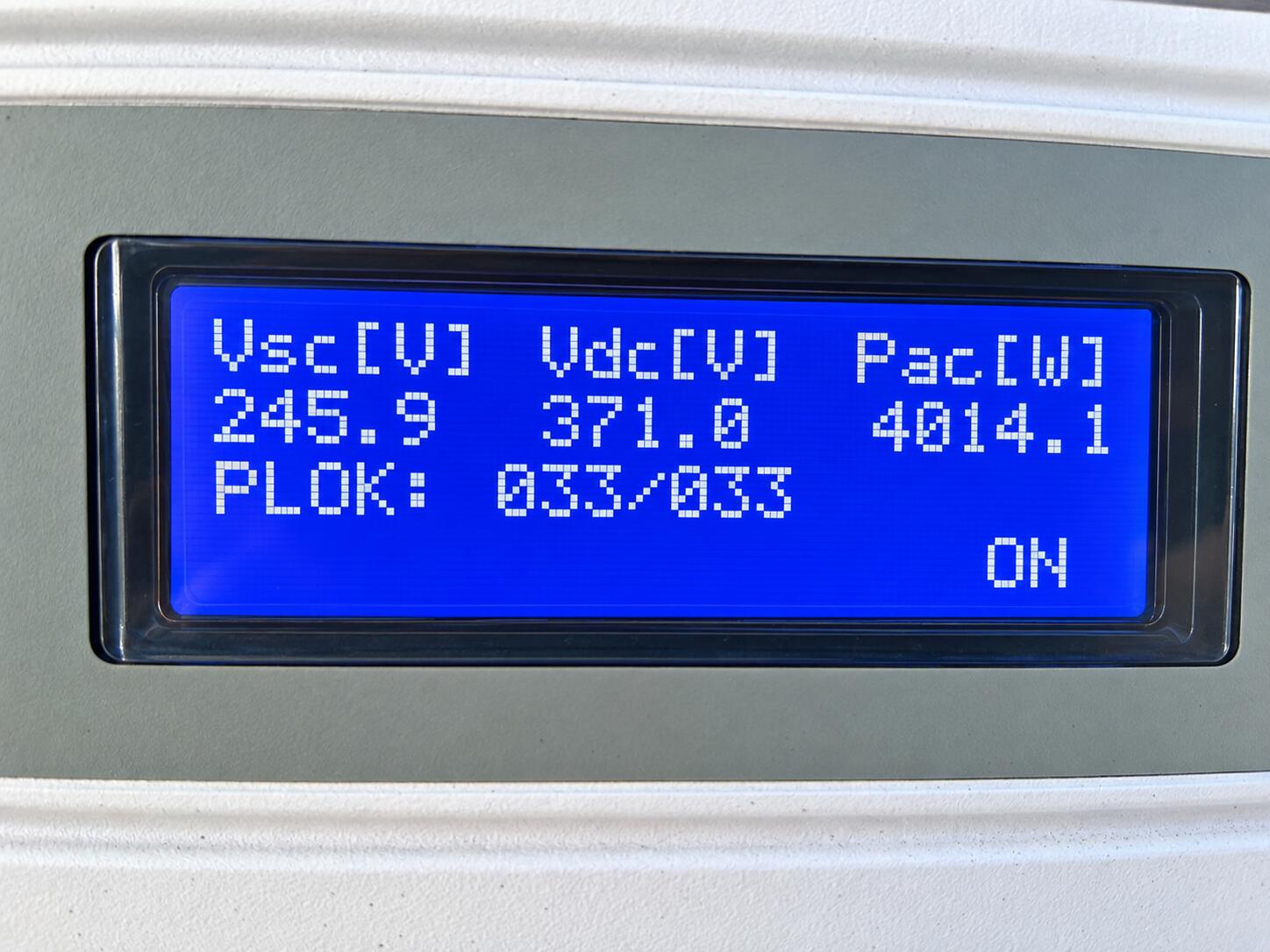Blue digital display on an electrical device showing voltage and power readings.