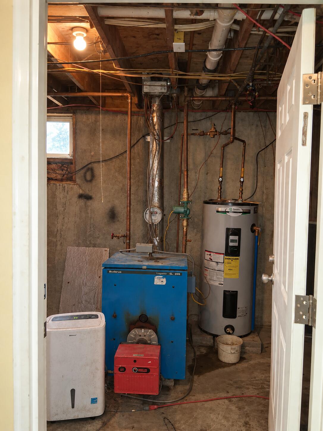 Basement utility room with a blue boiler, red burner, and gray water heater.