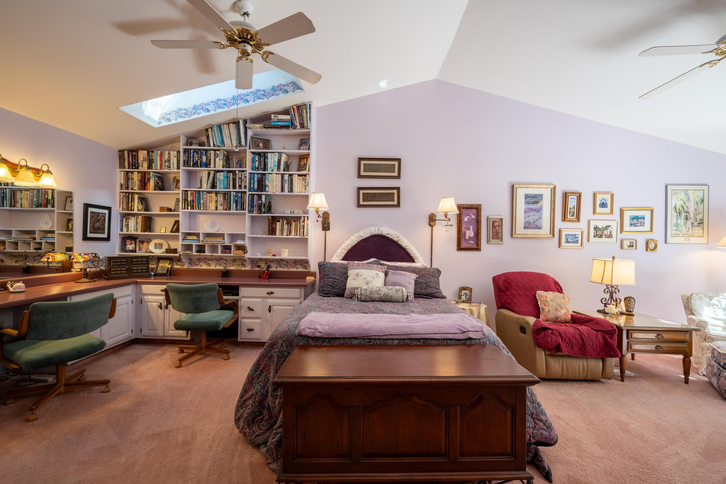 Bedroom with built-in bookshelves, a skylight, and a large wooden chest at the foot of the bed.