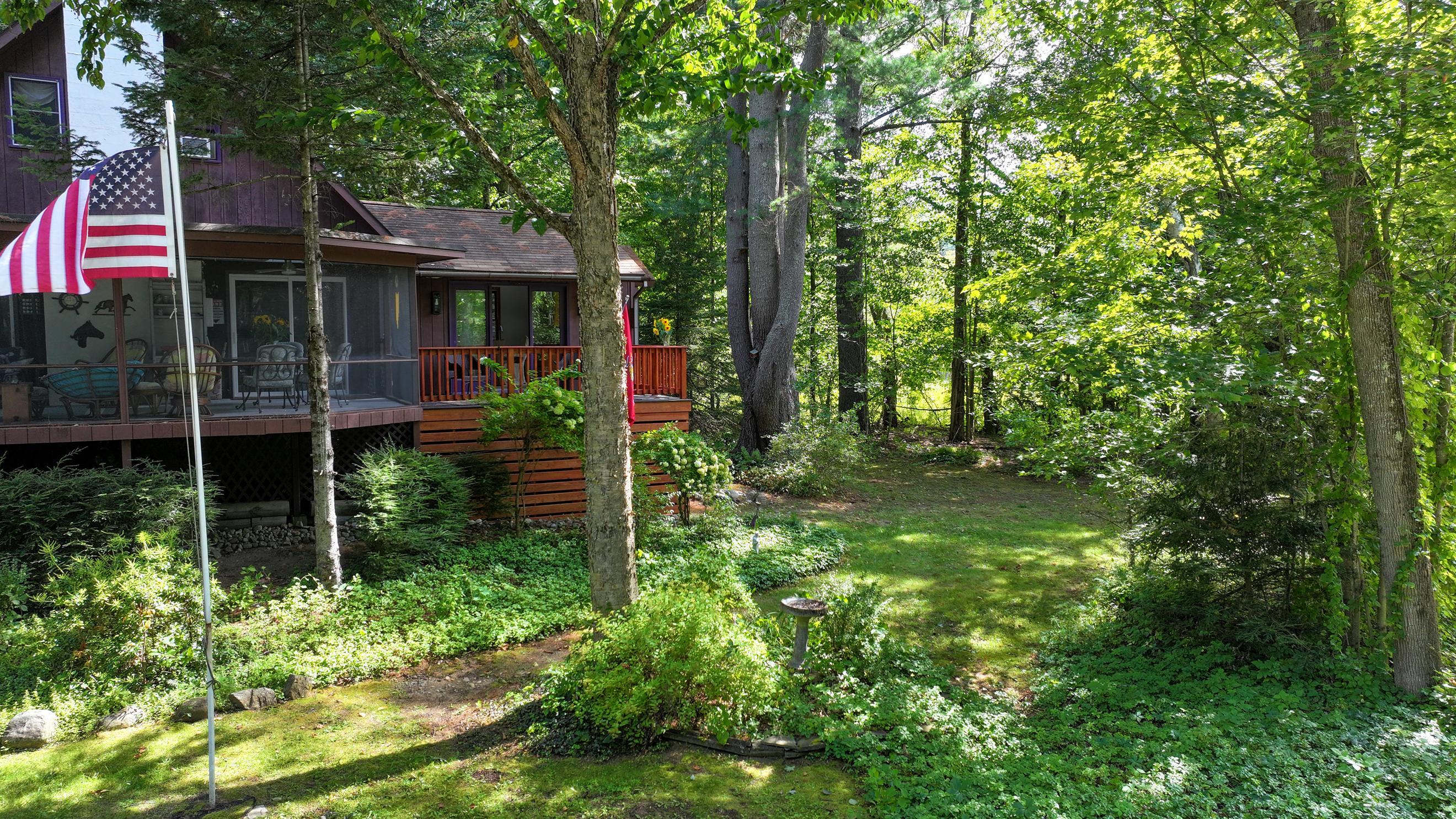 Wooded cabin with a screened porch, deck, garden, and American flag