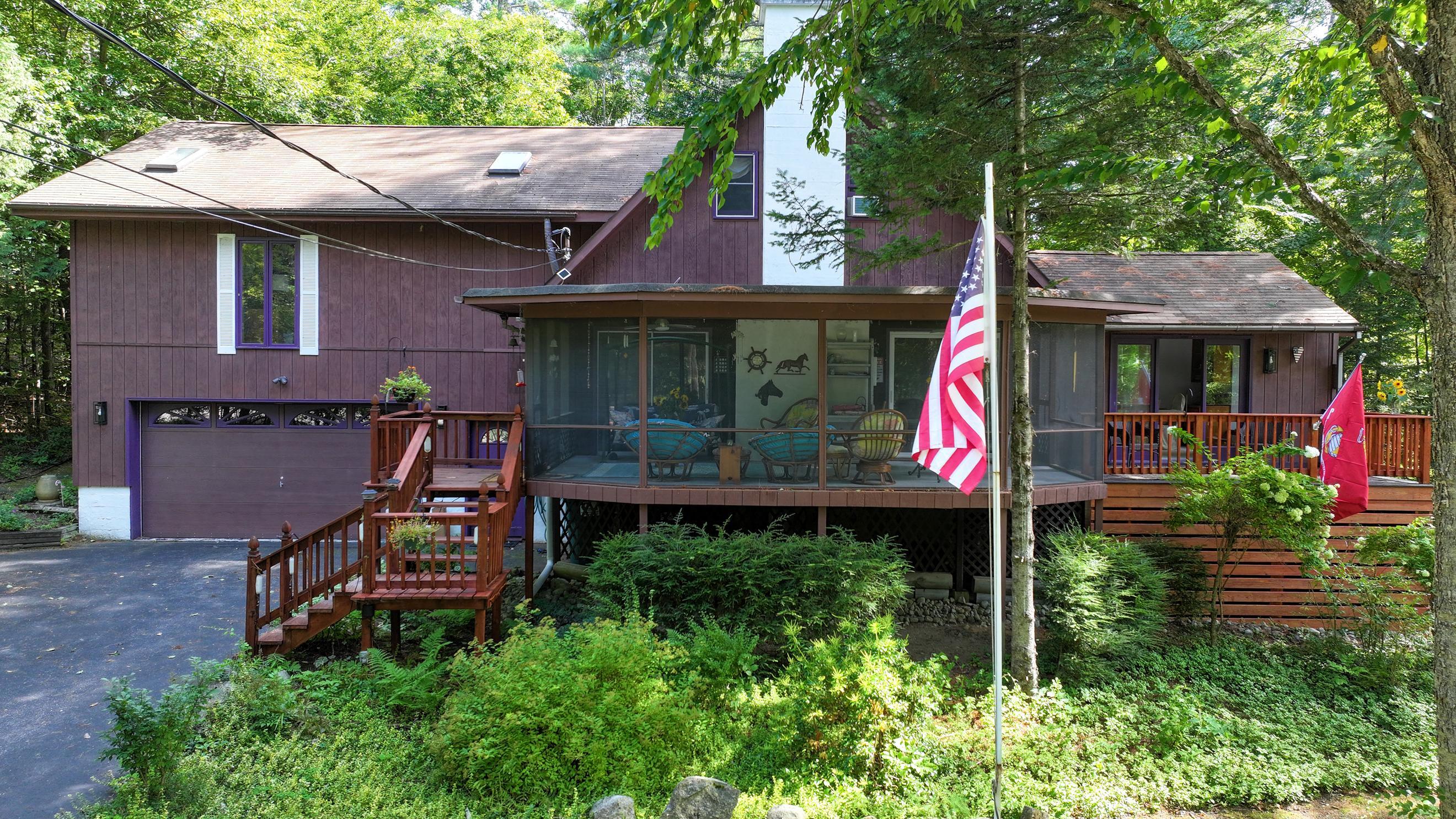 Wooded home with a screened porch, wooden decks, and an American flag.