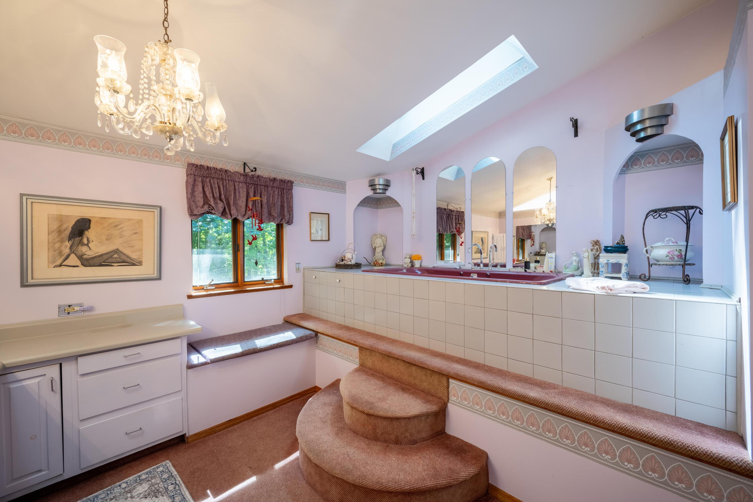 Bathroom with a raised tiled soaking tub, arched mirrors, and a large skylight.