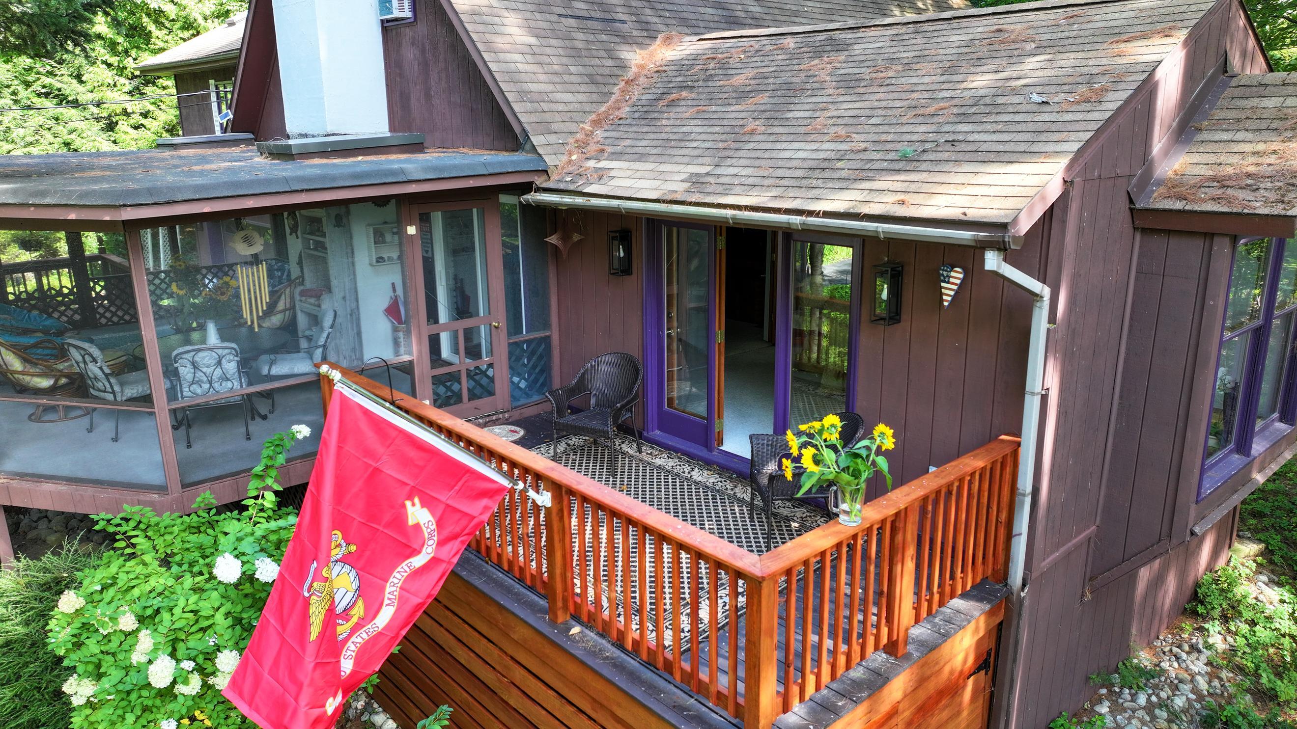 Home exterior with a raised deck, screened porch, and red Marine Corps flag.
